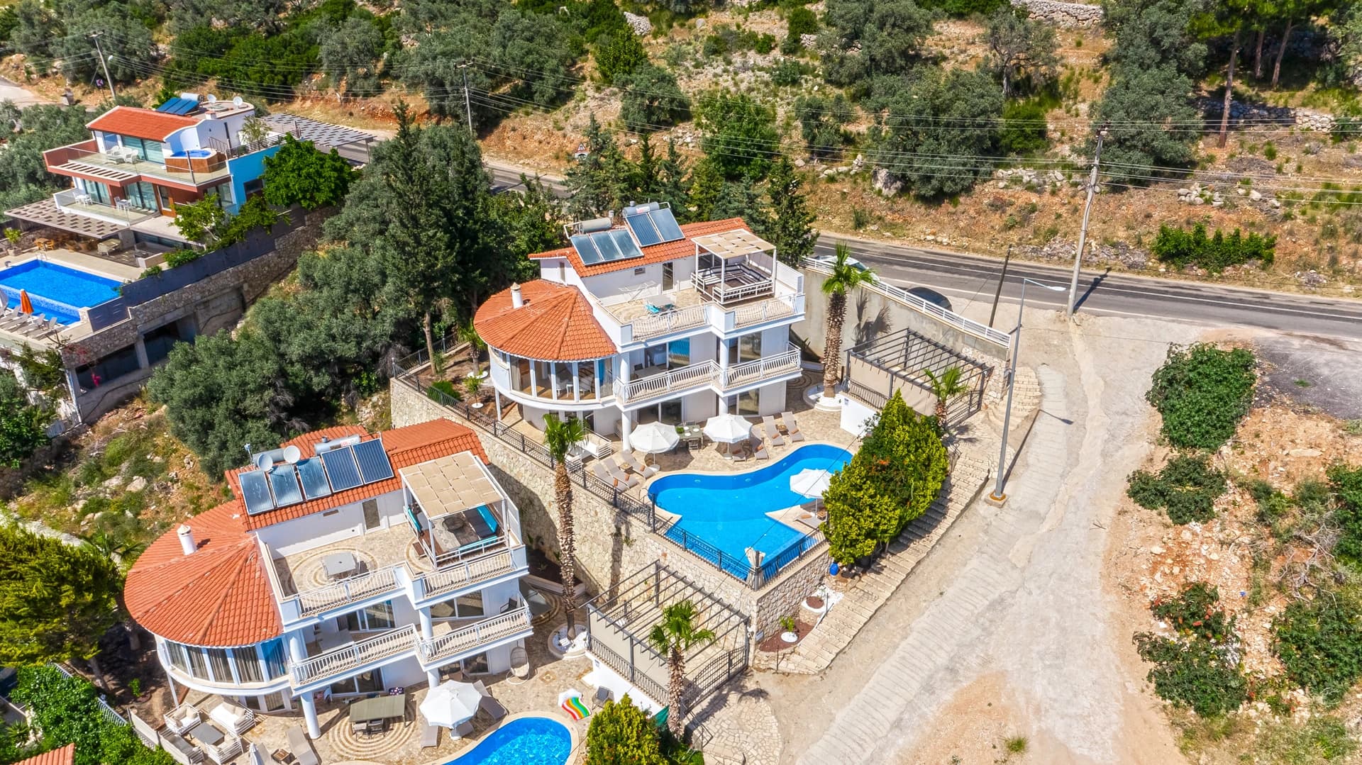 Aerial view of the complete luxury villa complex with pool, multiple terraces, and hillside setting.