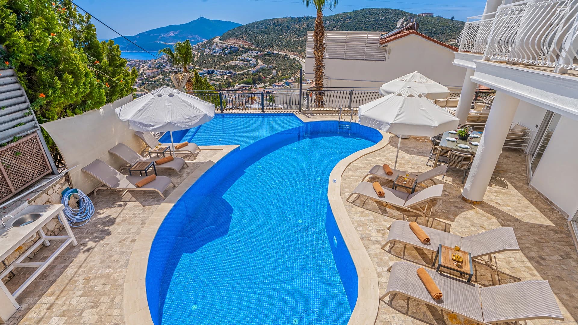 Stunning pool area with panoramic views of mountains, sea, and lush surroundings.