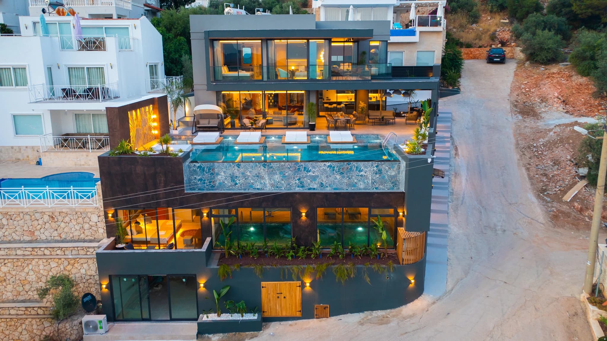 Contemporary multi-story villa with terraced pool and sophisticated outdoor lighting.