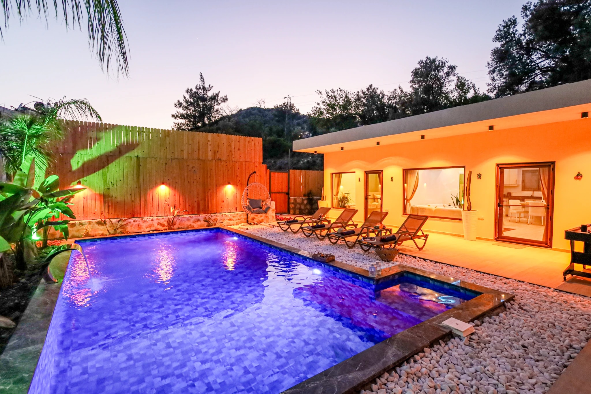 Scenic pool overlooking mountains with tropical landscaping and terrace seating.