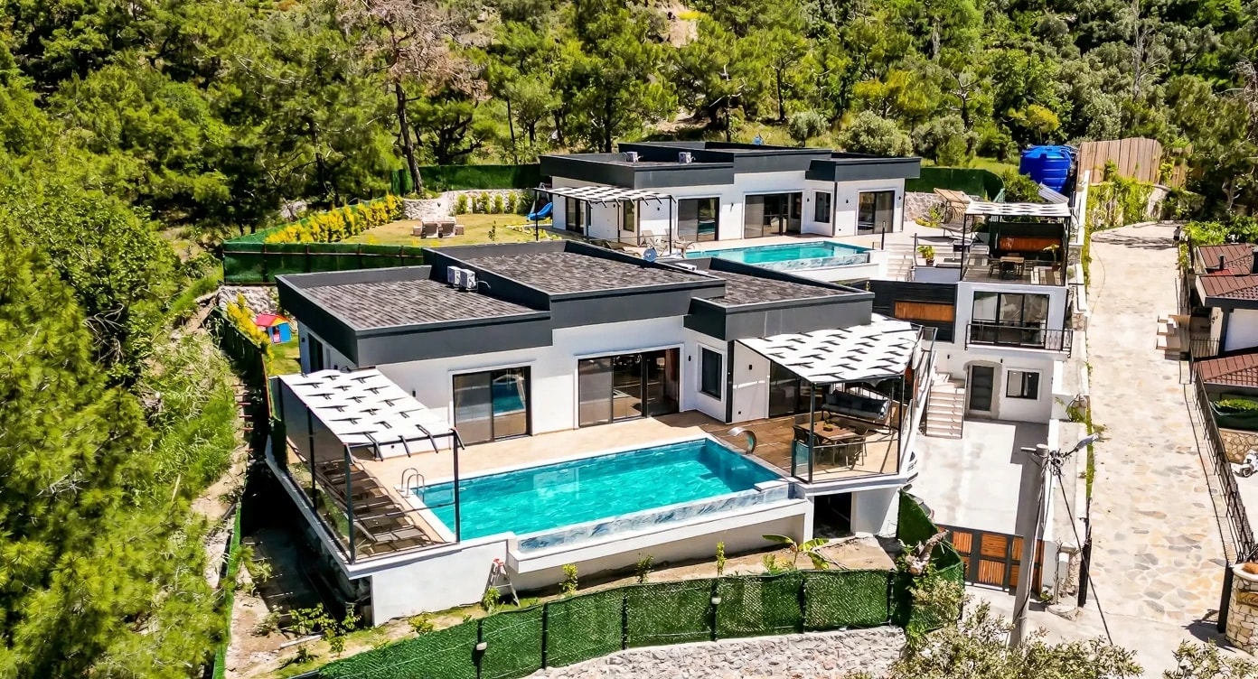Aerial view of contemporary villa with turquoise pool, modern architecture, and lush garden setting.