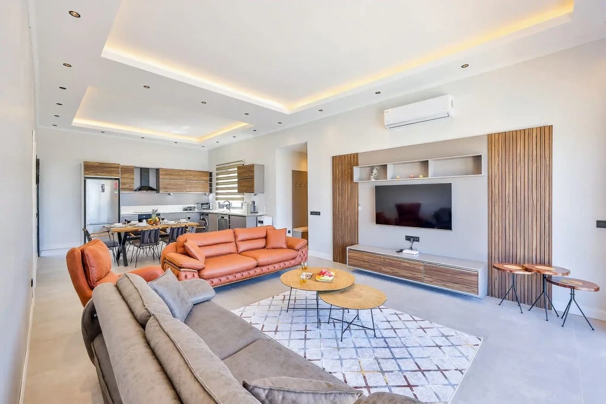 Bright modern living space with sophisticated gray and orange furniture and integrated kitchen.