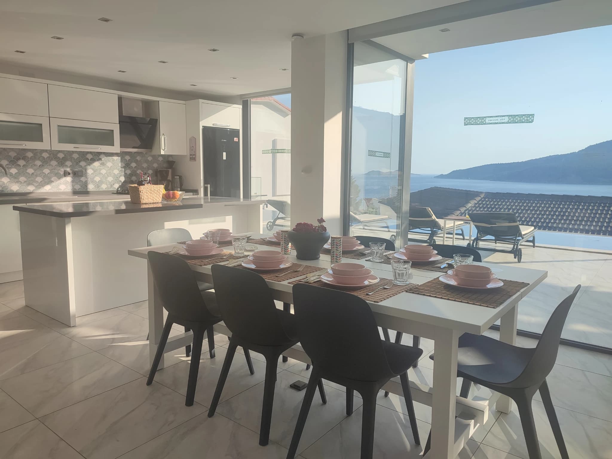 Contemporary kitchen with integrated dining area and floor-to-ceiling views of the landscape.