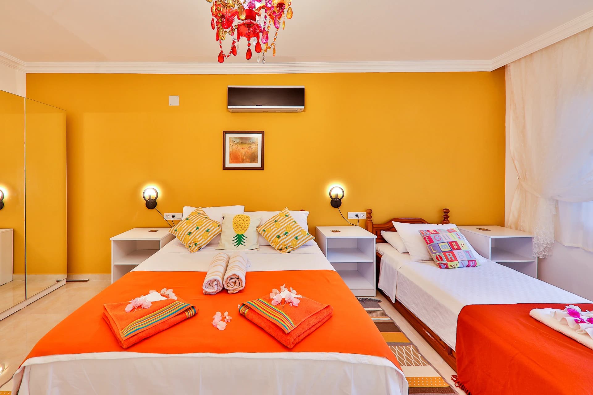 Family bedroom with queen and single beds, vibrant orange walls, and coordinated furnishings.
