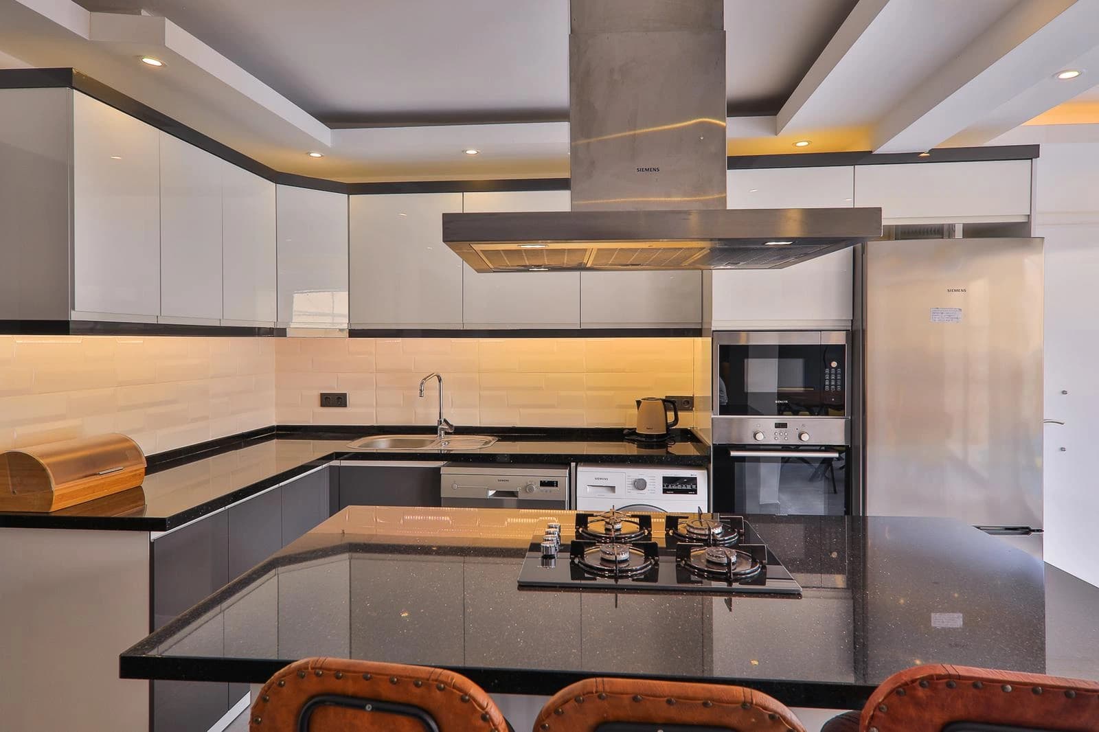 Modern fully-equipped kitchen with modern appliances, gas cooktop, and spacious island counter.