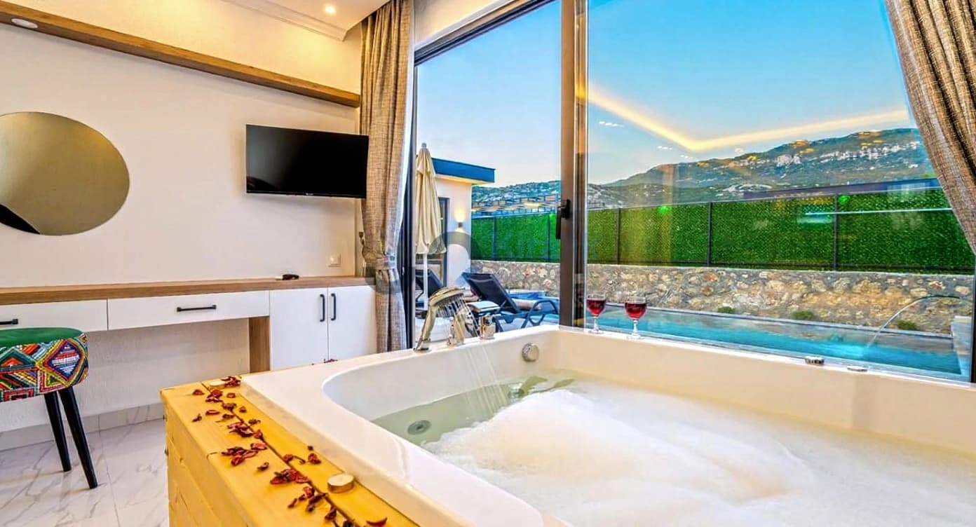 Stunning bathroom featuring large soaking tub with sweeping mountain and pool views through floor-to-ceiling windows.