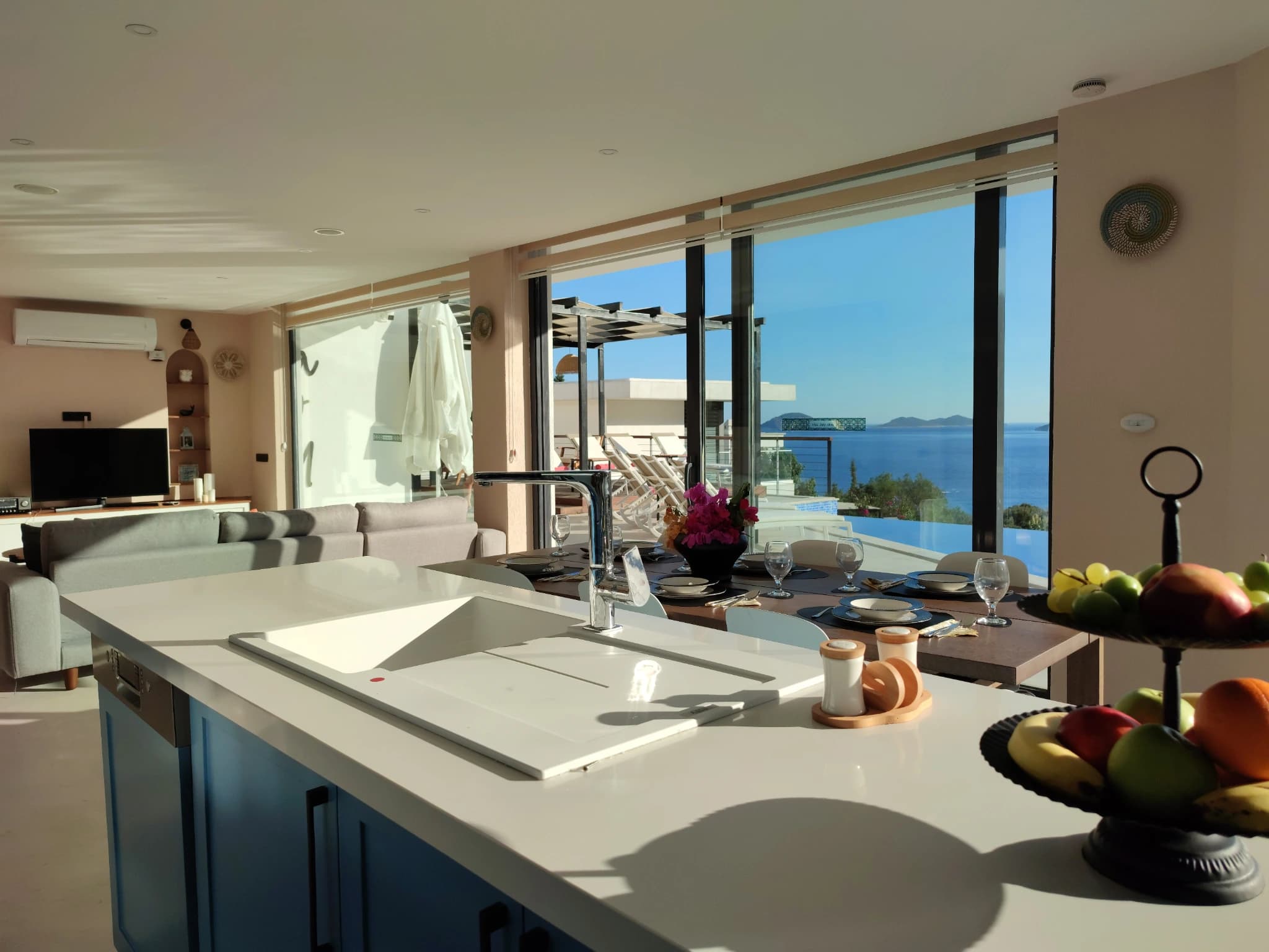 Bright kitchen with white countertops and island, overlooking the sea and terrace.