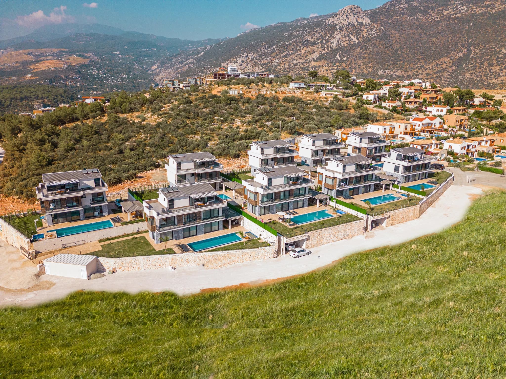 Aerial view of luxury modern villas with private pools nestled in mountain landscape.