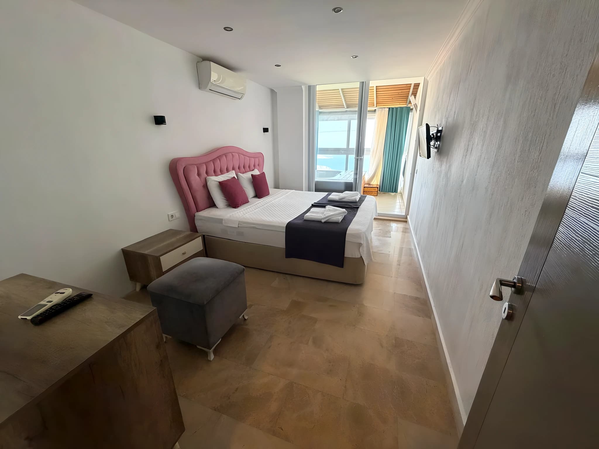 Bright bedroom with king bed, balcony overlooking the sea, and modern amenities.