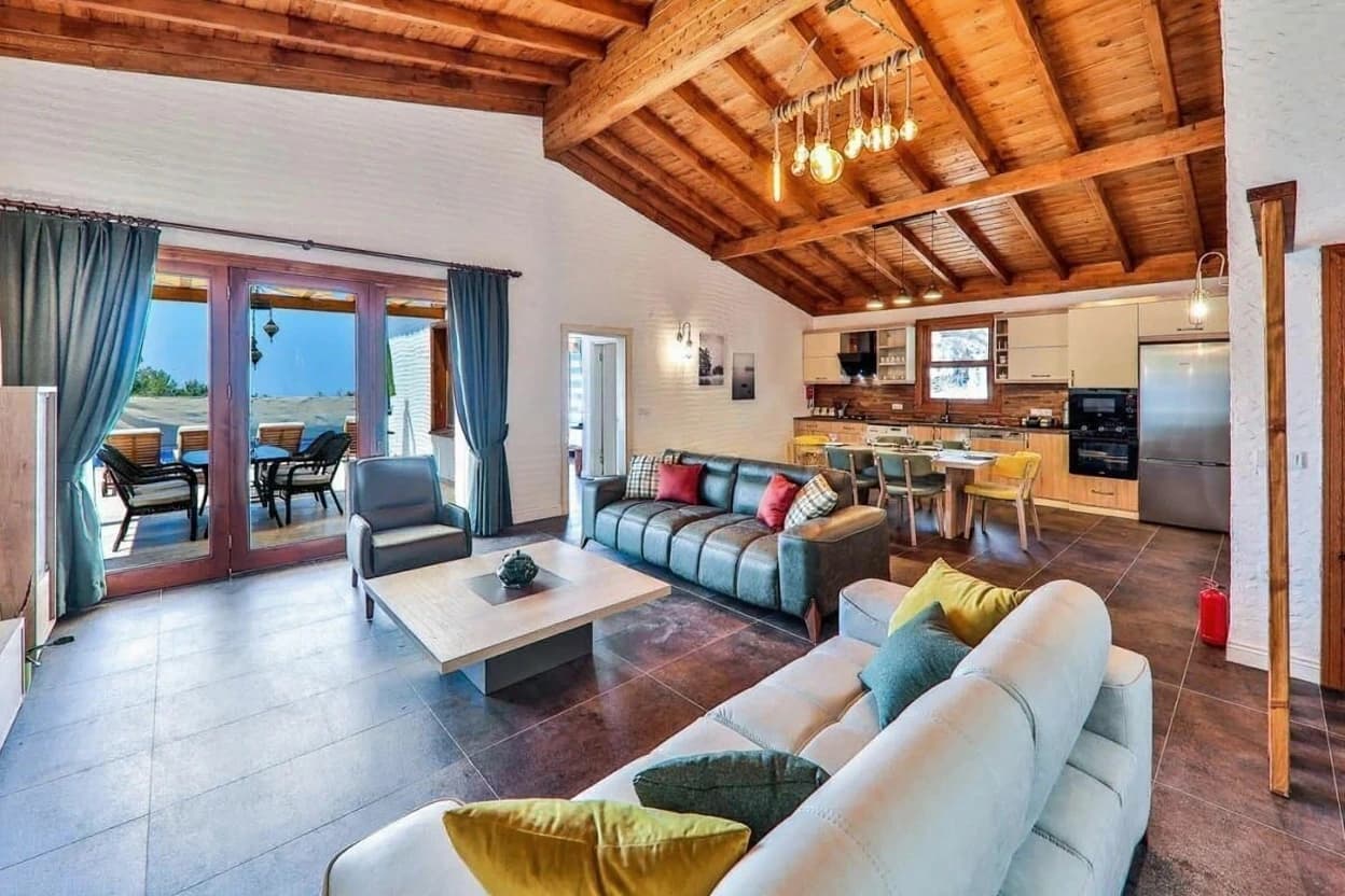 Kaş İslamlar'da Özel Havuzlu, Jakuzili ve Deniz Manzaralı 2 Yatak Odalı Korunaklı Villa – Spacious open-plan living area with exposed wooden beams, modern furnishings, and direct terrace access.