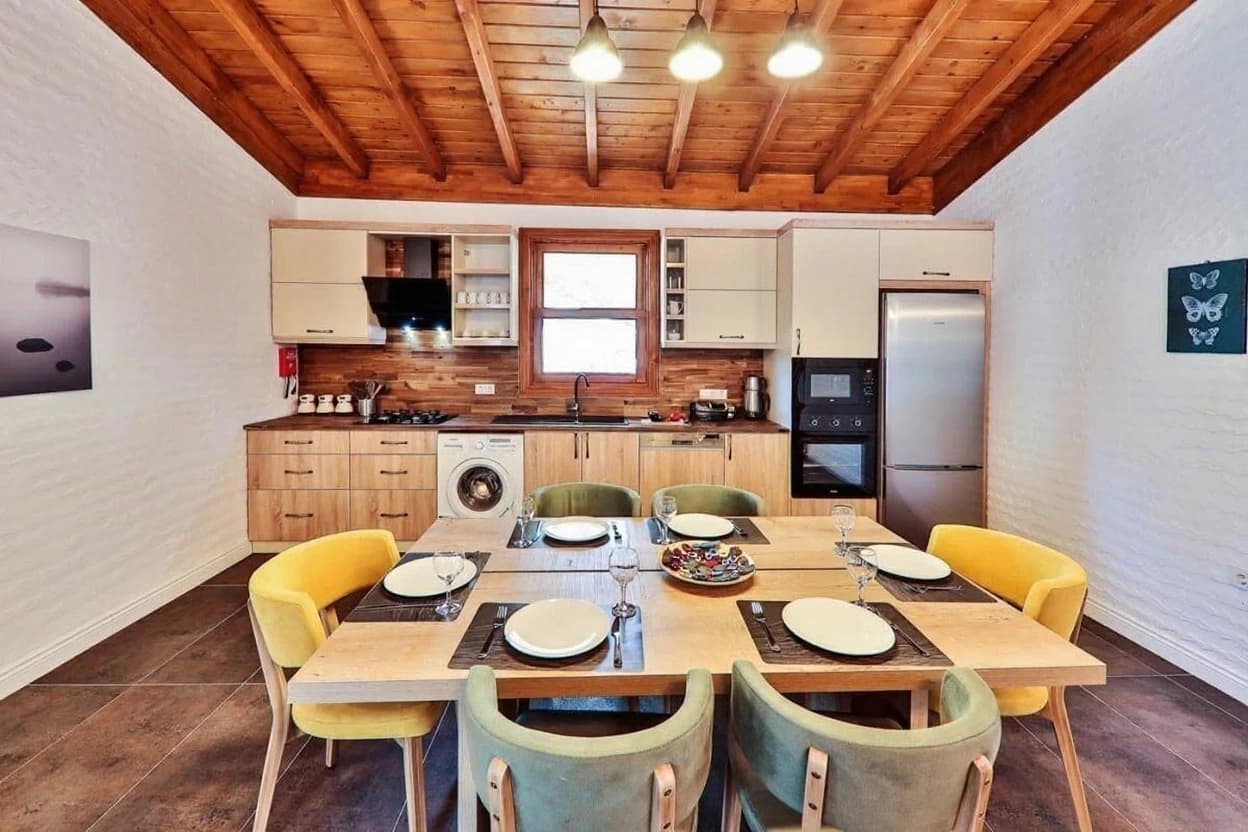 Kaş İslamlar'da Özel Havuzlu, Jakuzili ve Deniz Manzaralı 2 Yatak Odalı Korunaklı Villa – Modern dining kitchen with wooden beamed ceiling, fully-equipped kitchen, and dining seating for six.