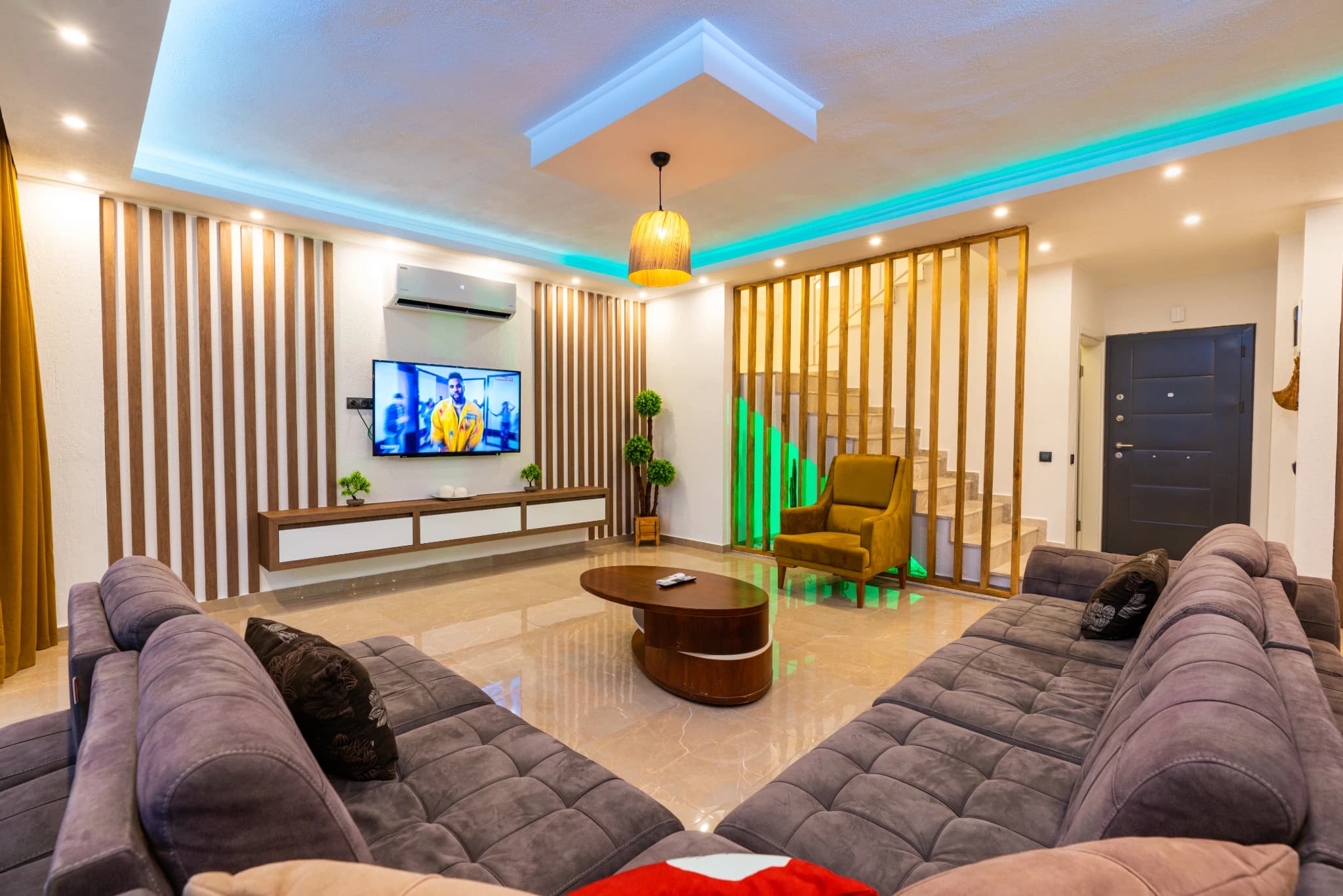 Modern living area with dual sectional sofas facing a wall-mounted TV.