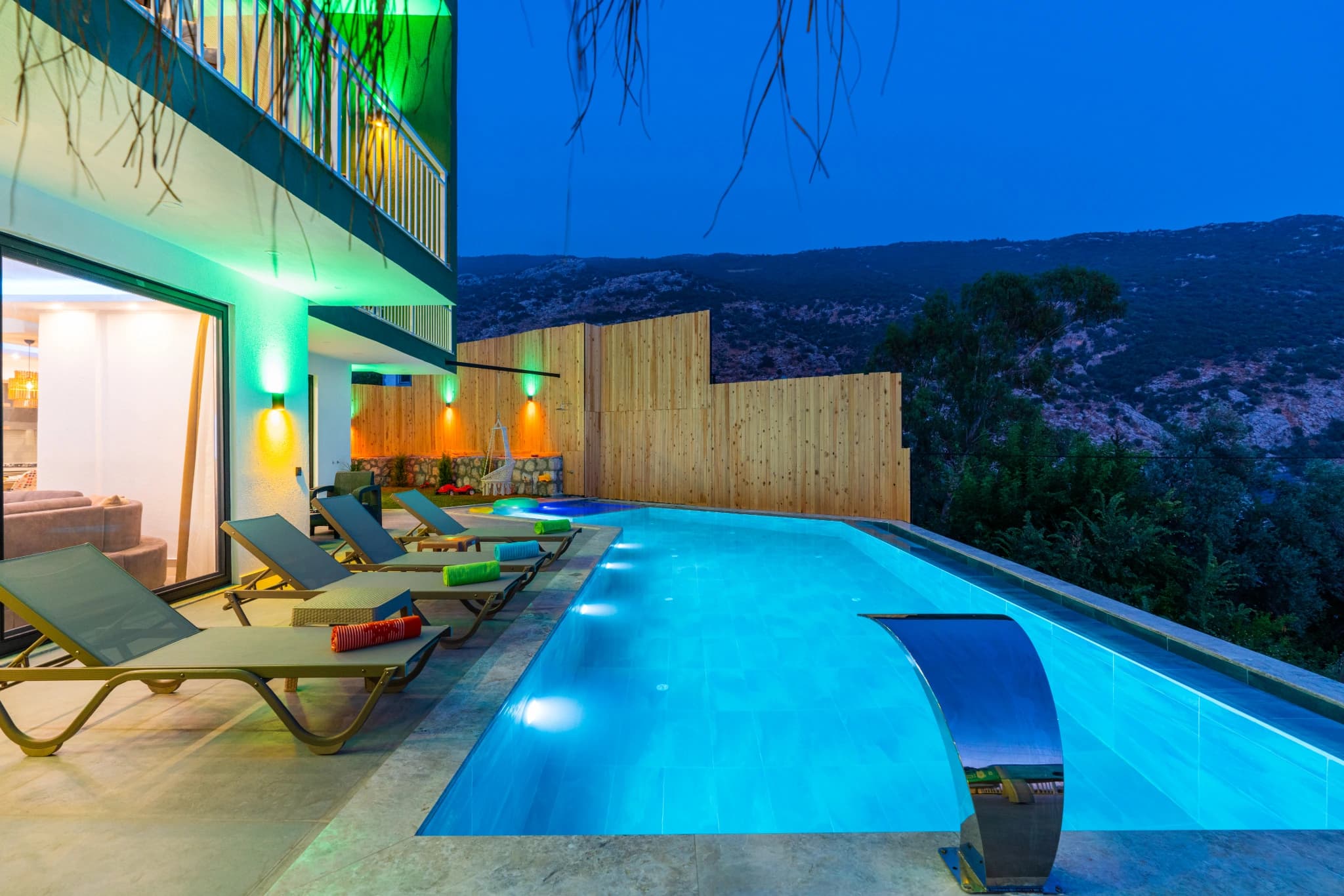 Luxurious infinity-edge pool with loungers and dramatic mountain views at twilight.