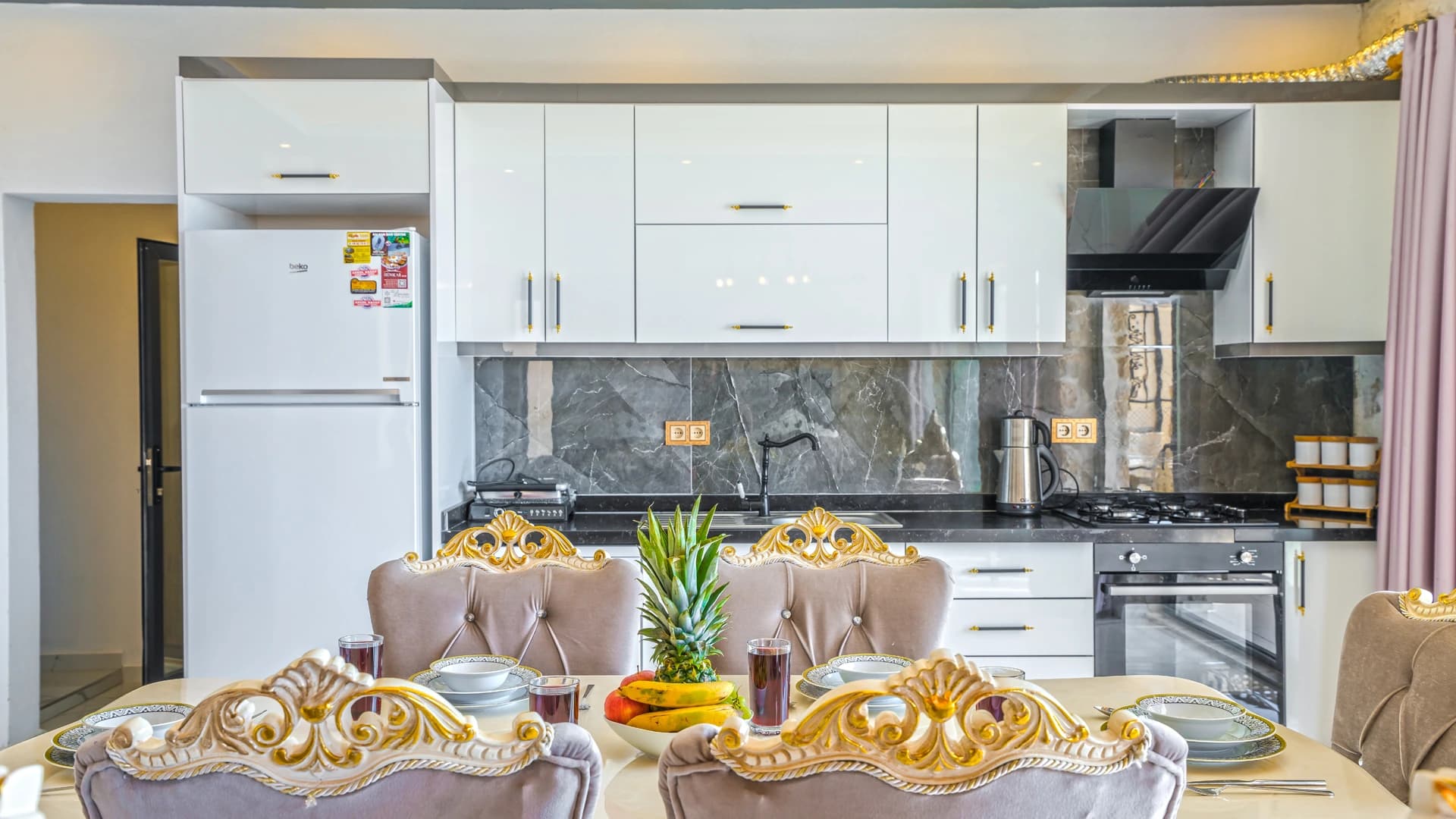 Modern kitchen with white cabinetry, integrated dining area, and decorative table setting.
