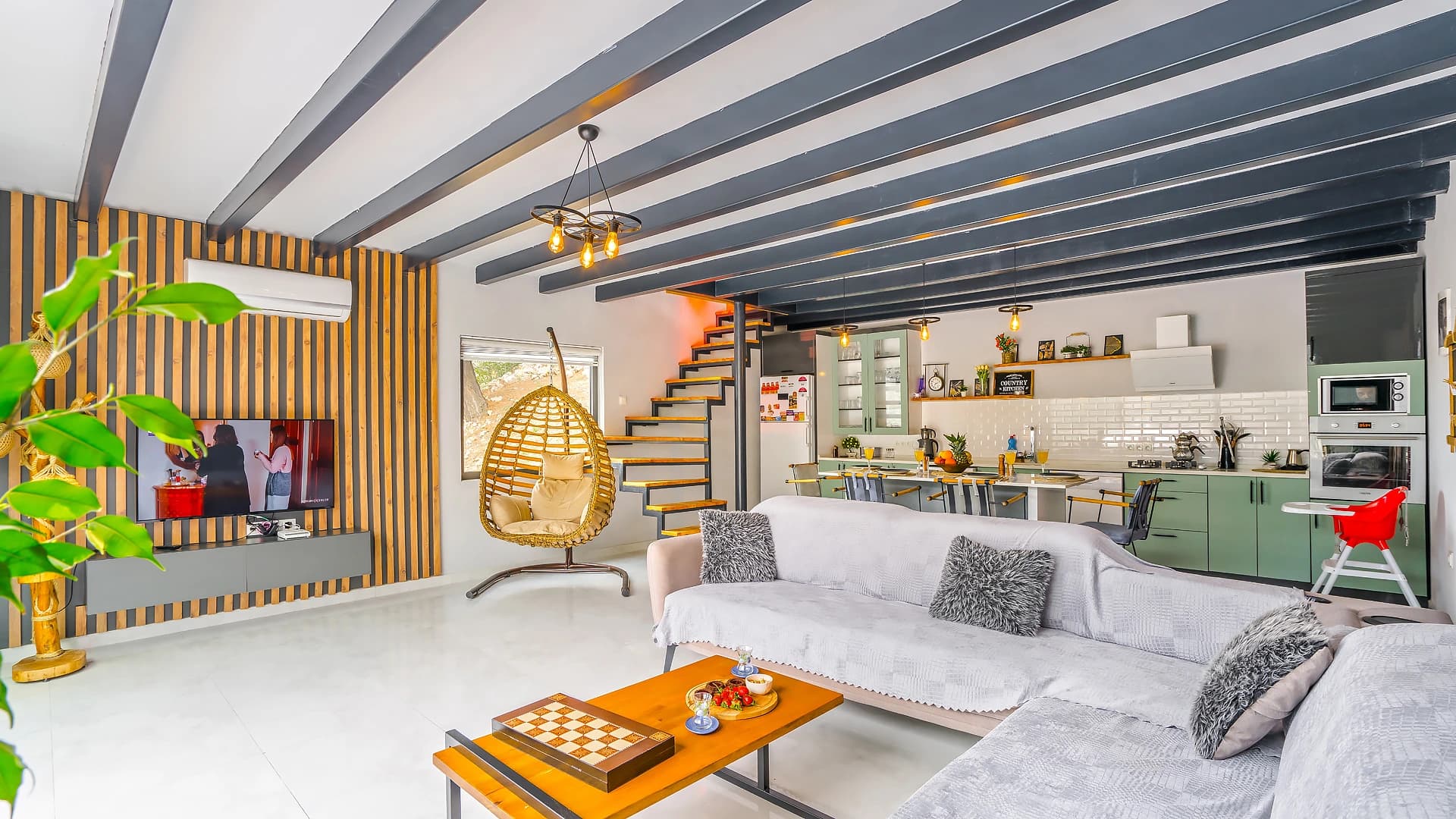 Multi-level living space with sofa, game table, and integrated kitchen.