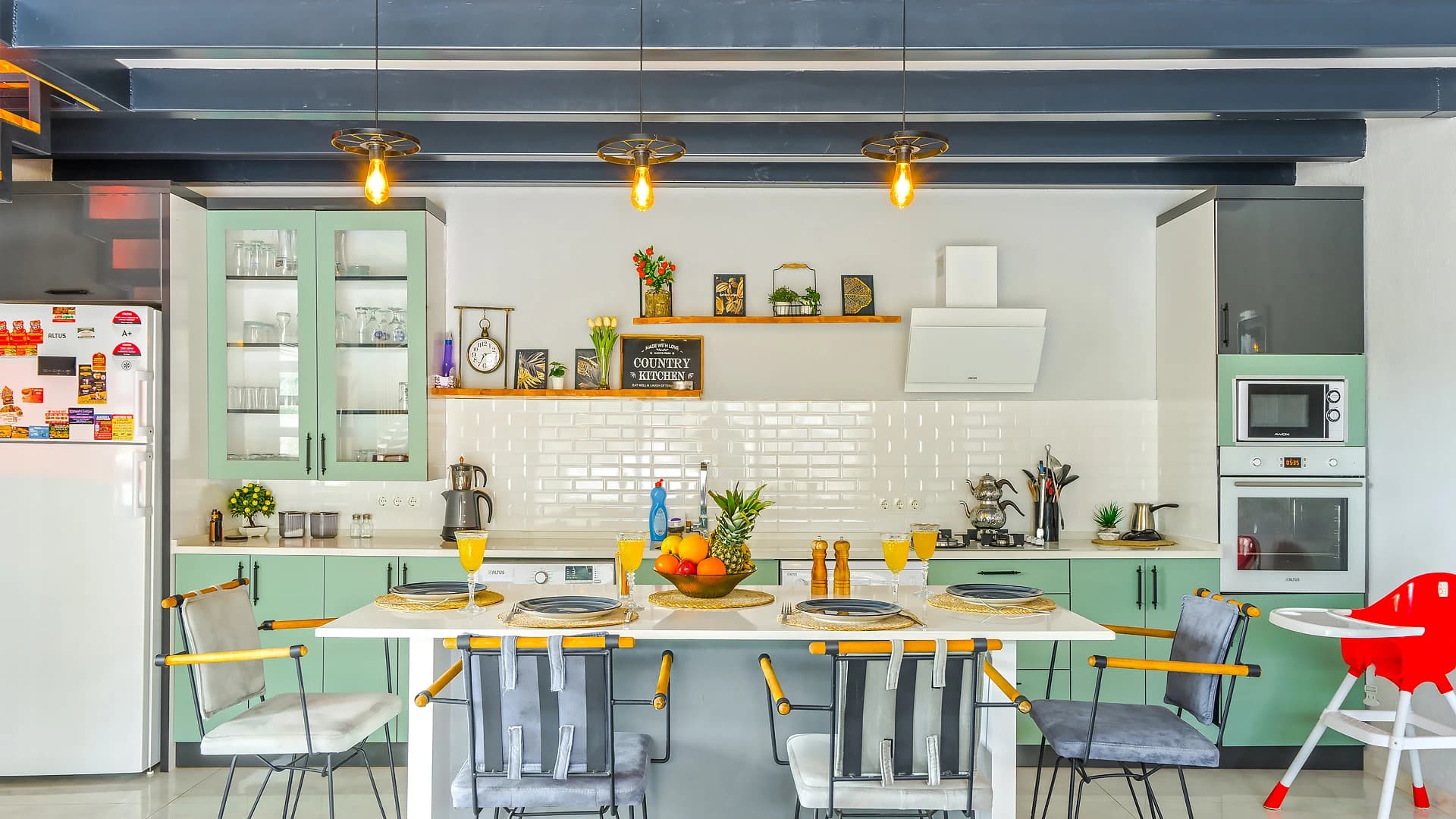 Modern kitchen with green cabinets, white subway tile backsplash, and dining area.