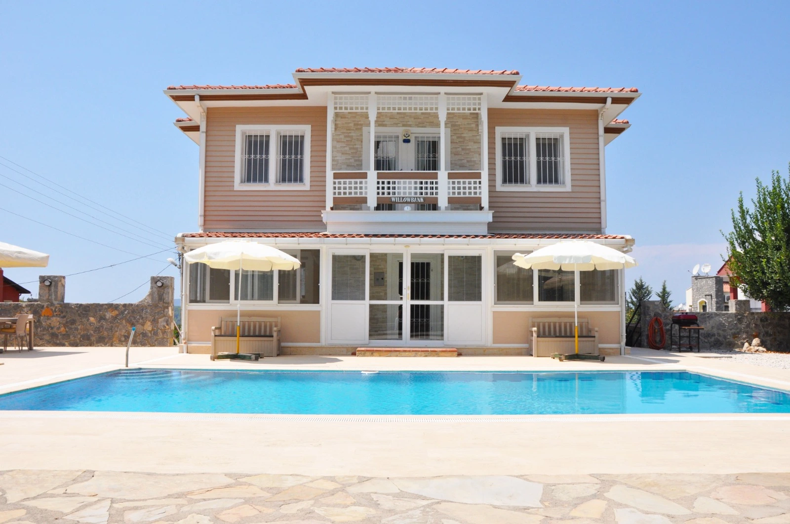 Front elevation of the villa with pool and mountain backdrop.