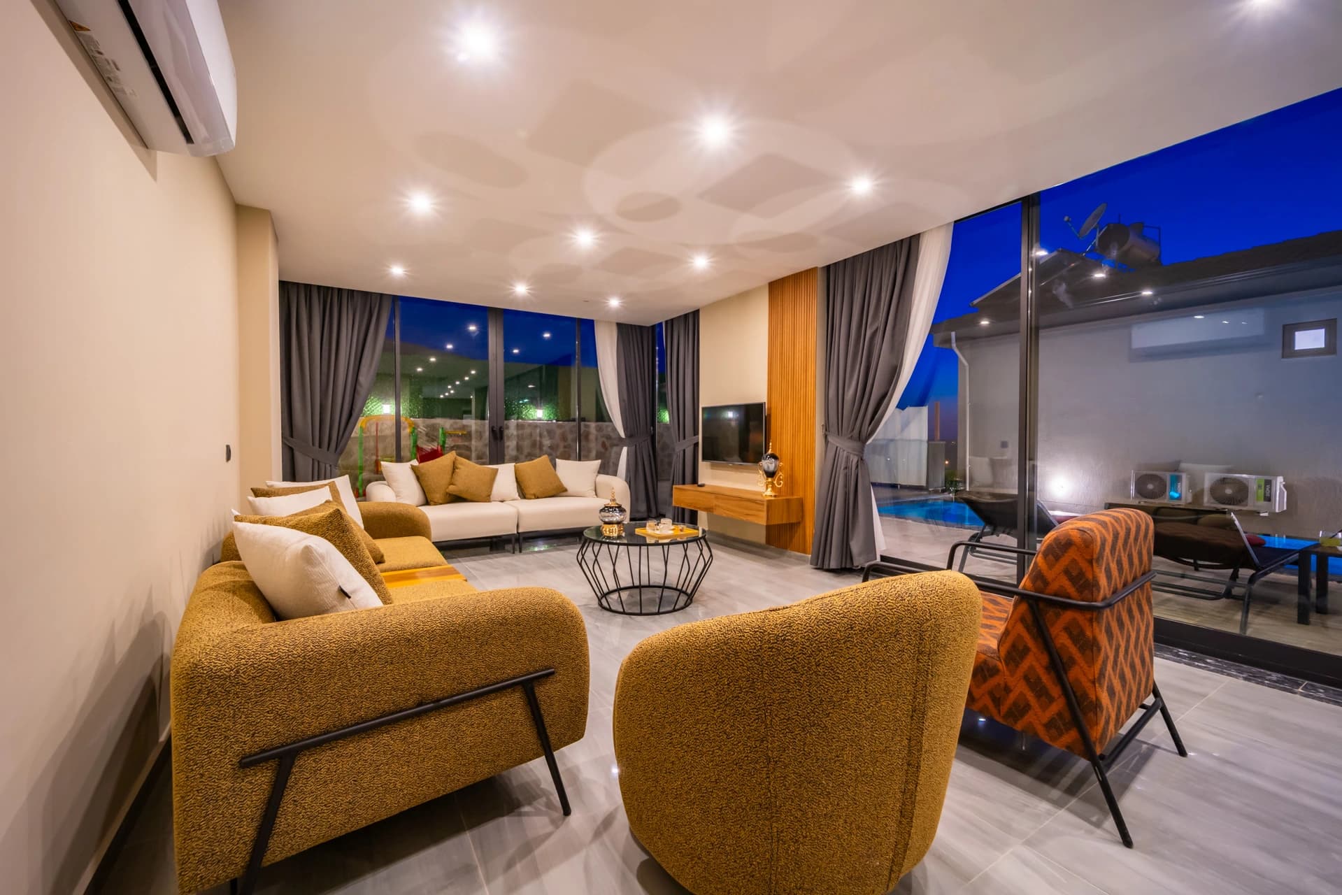 Spacious living room with panoramic pool and night views.
