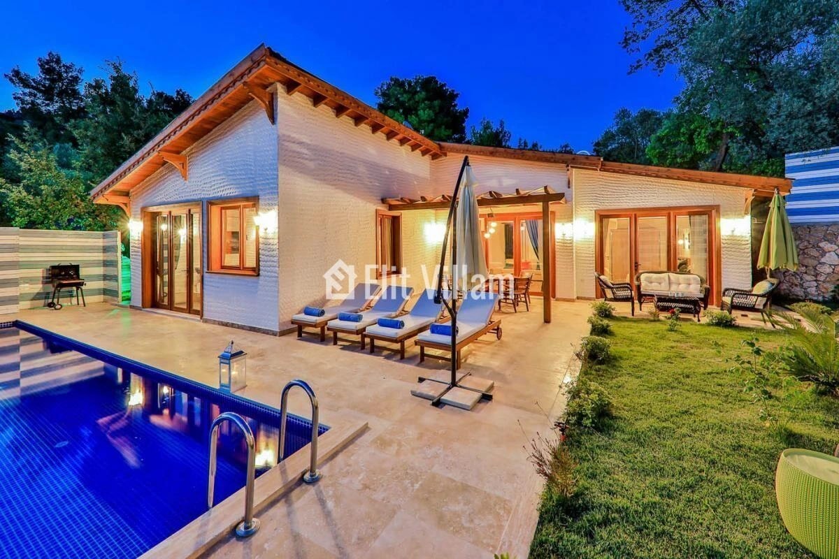 Stunning twilight view of the villa with illuminated pool and lounge area.