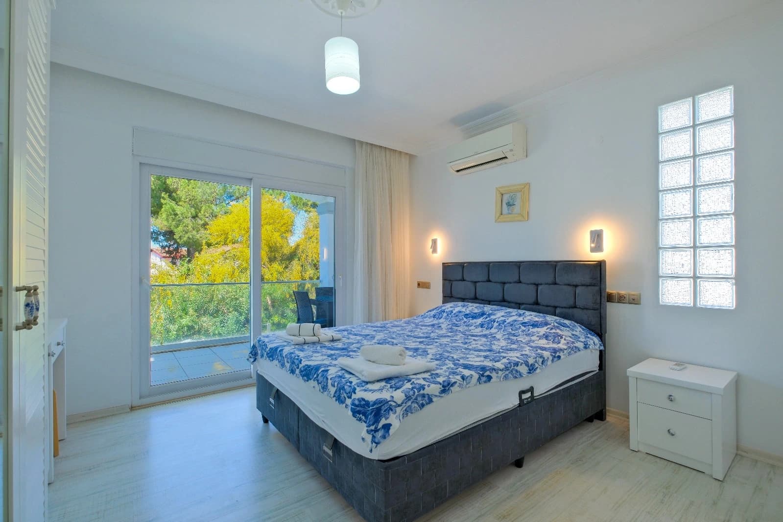 Bright master bedroom with balcony access and pool/garden views.