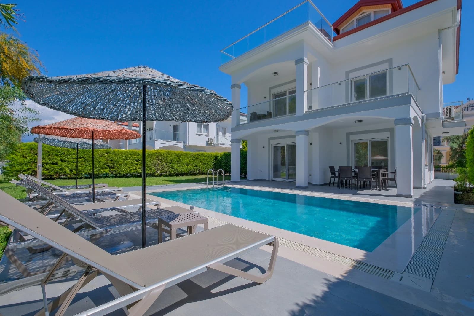 Resort-style pool with elegant lounging area and modern villa exterior.