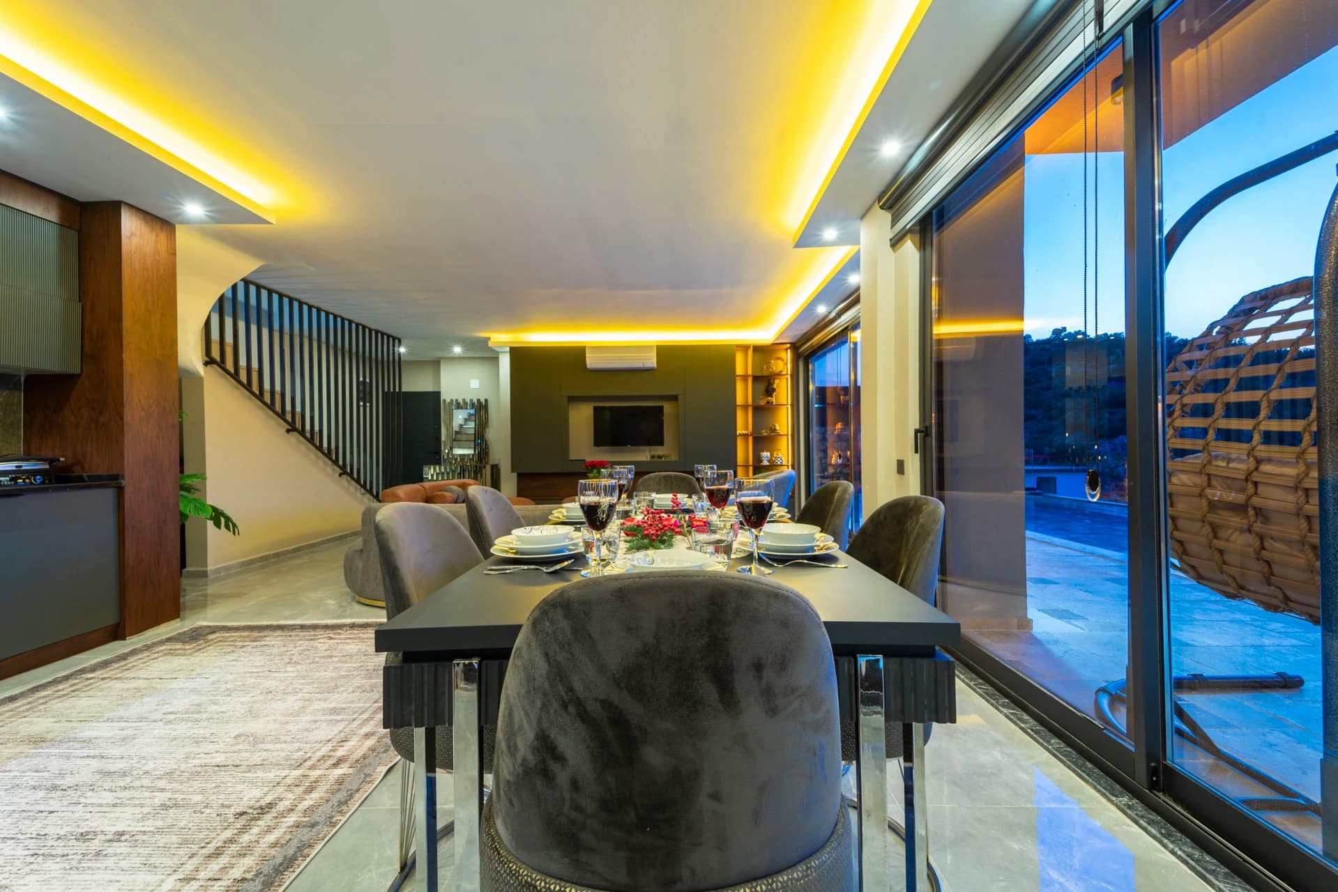 Elegant dining room with table setting overlooking a glowing poolside terrace and mountain views at twilight.