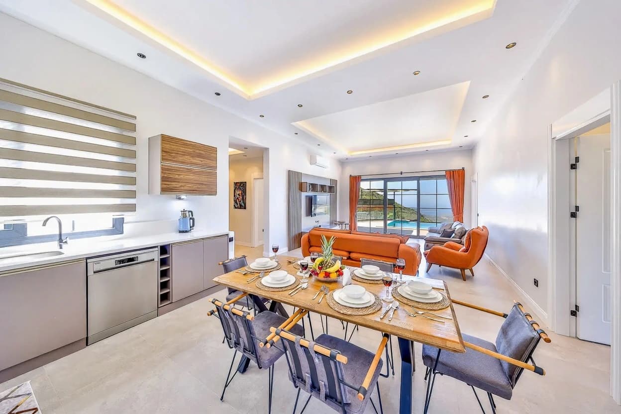 Open-plan dining and living area with full kitchen, seating for six, and views to the pool.