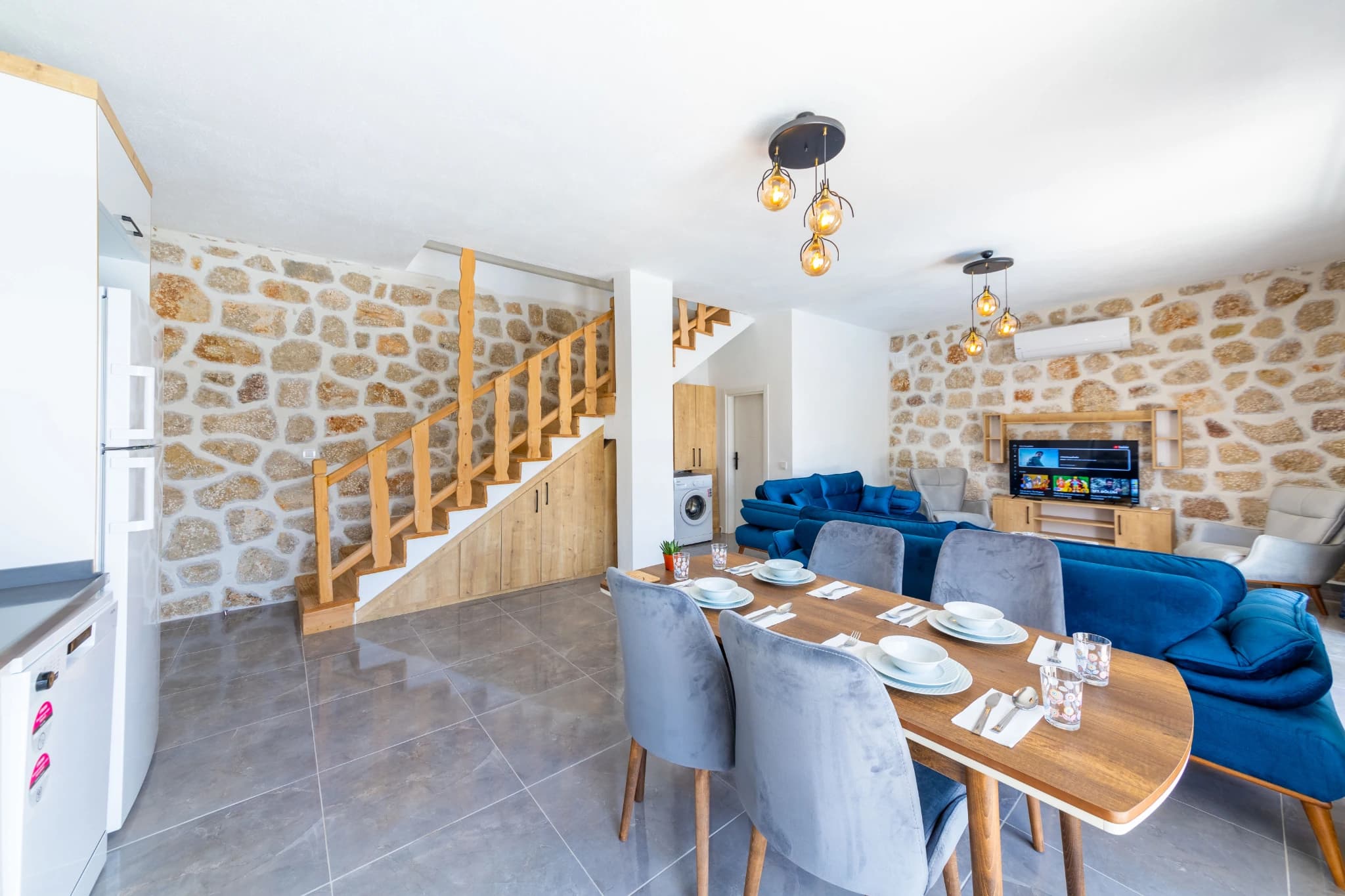 Dining table in open-plan space with stone walls and access to living areas.