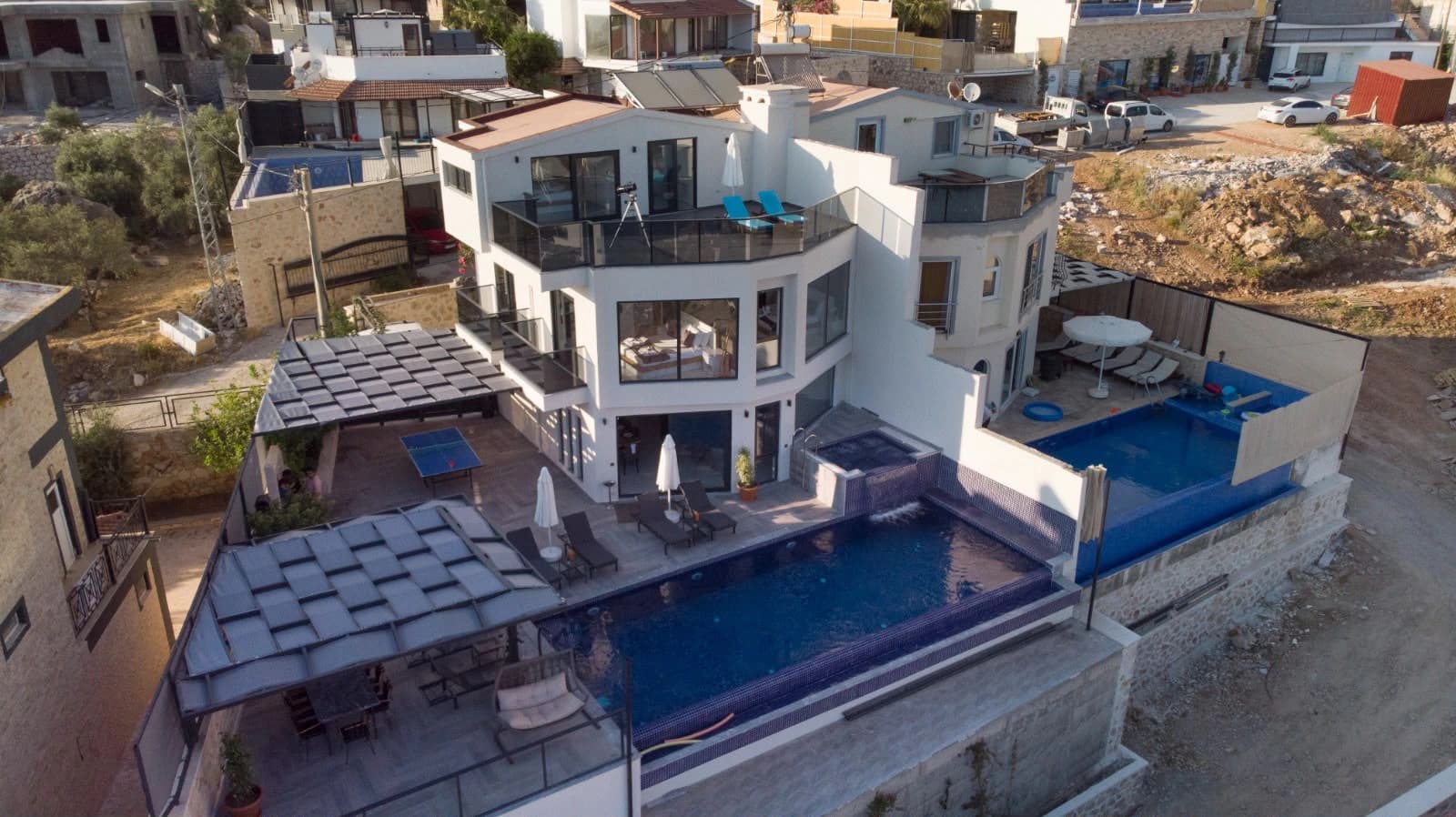 Aerial perspective of the entire modern villa with integrated pool areas.