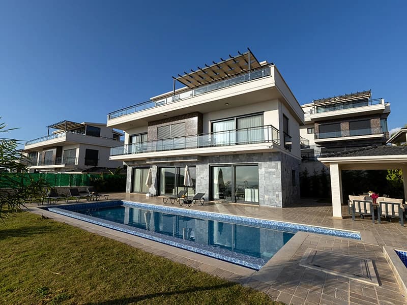 Modern luxury villa facade with integrated private pool, expansive terrace deck, and manicured gardens.