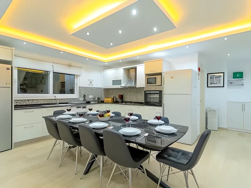 Contemporary kitchen with white cabinets and integrated dining area.