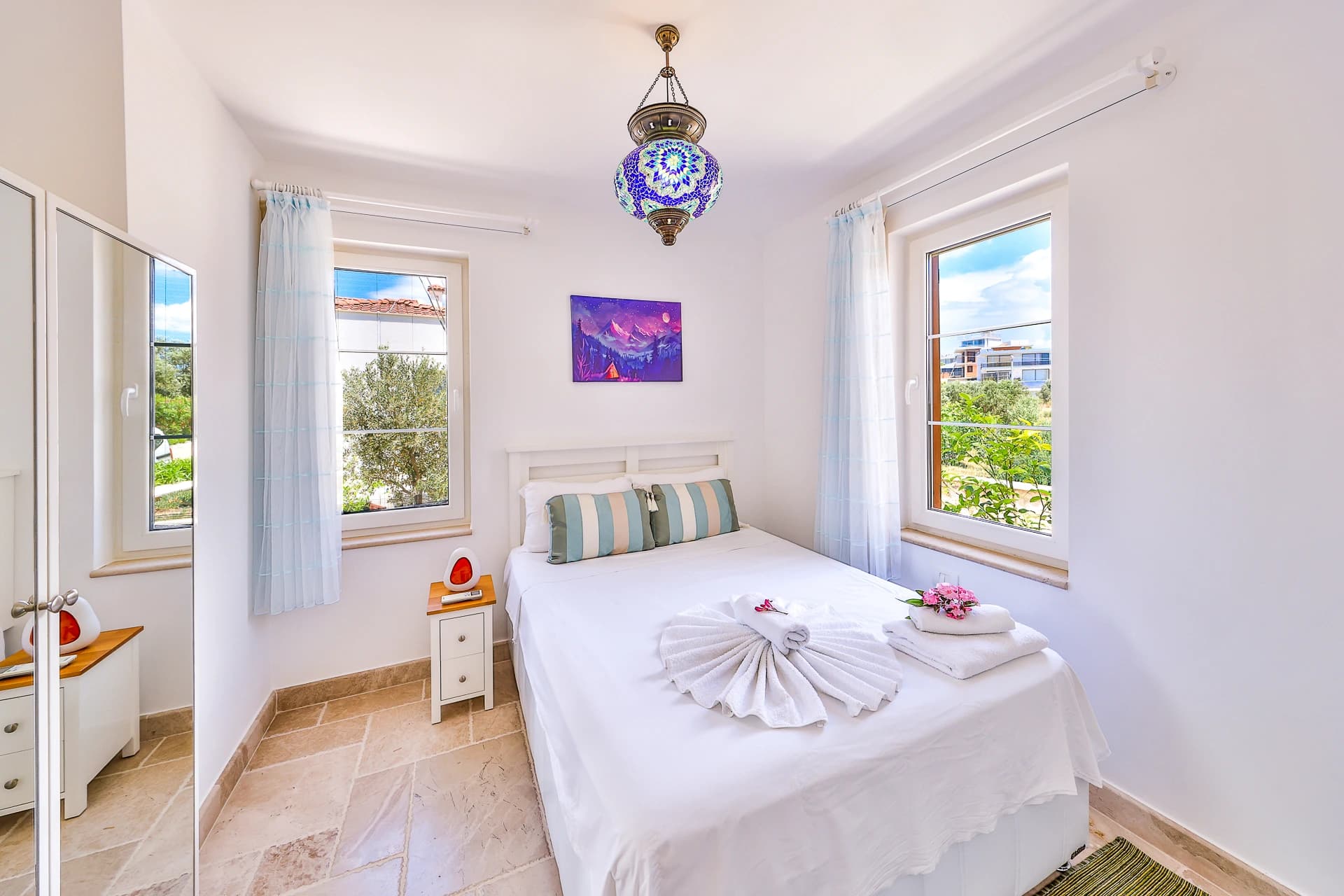 Light-filled bedroom with double bed and multiple windows offering sea views.