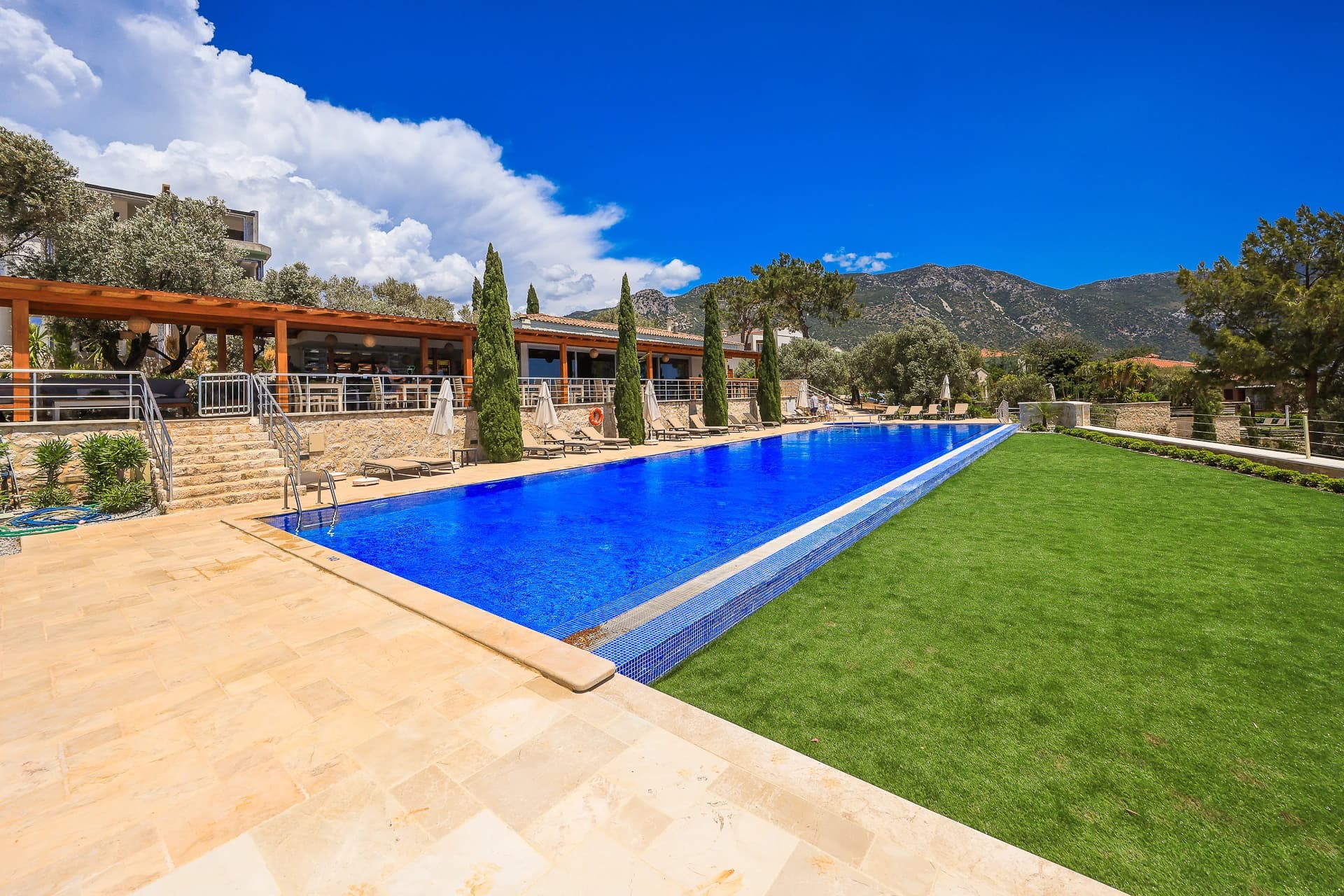 Elegant lap pool with manicured gardens and covered wooden dining pavilion.