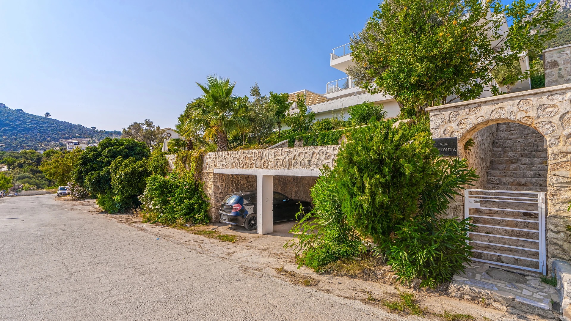 Garage and parking area with stone architecture surrounded by mature landscaping.