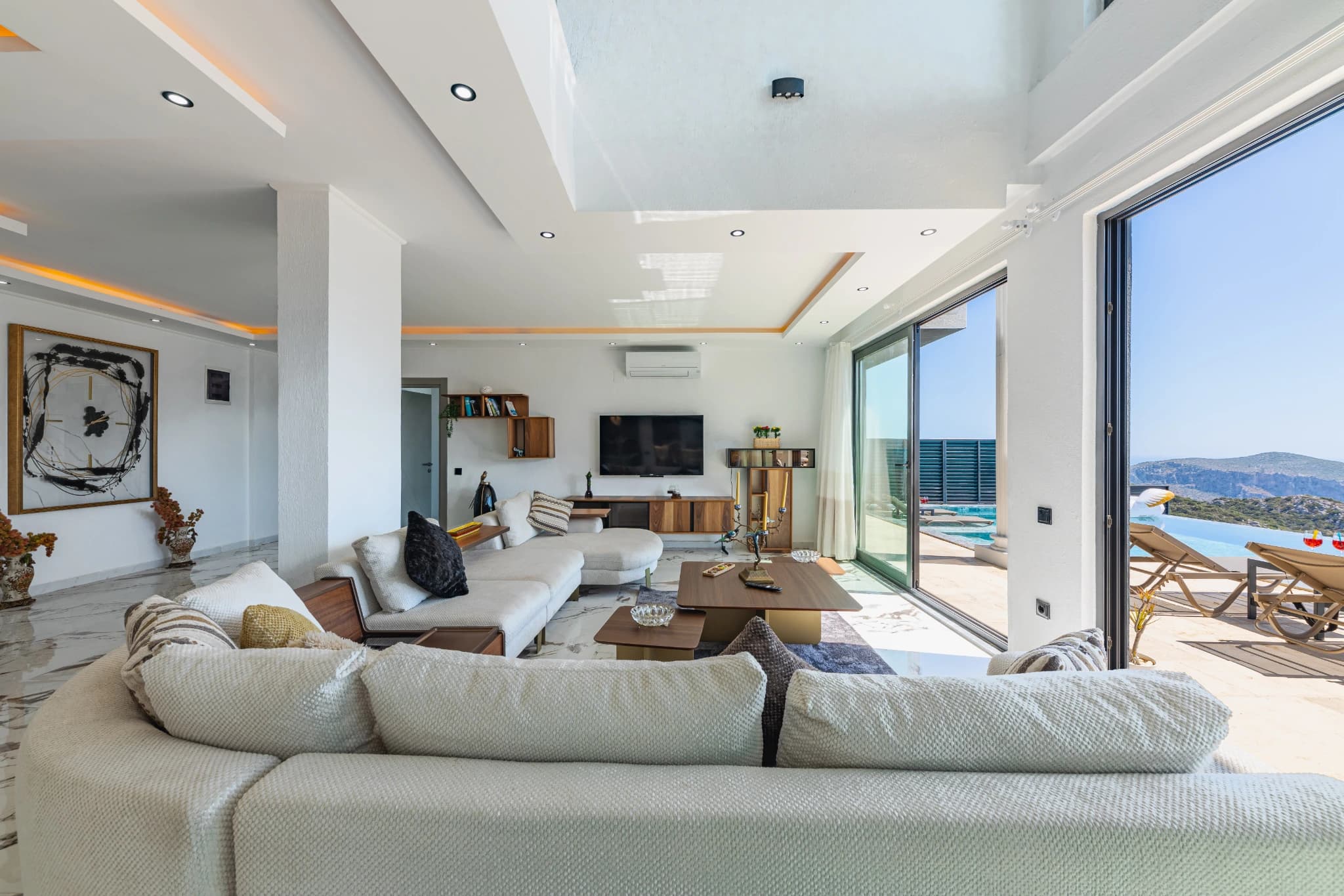 Contemporary living room with large seating area, smart TV, and expansive views to pool and sea.