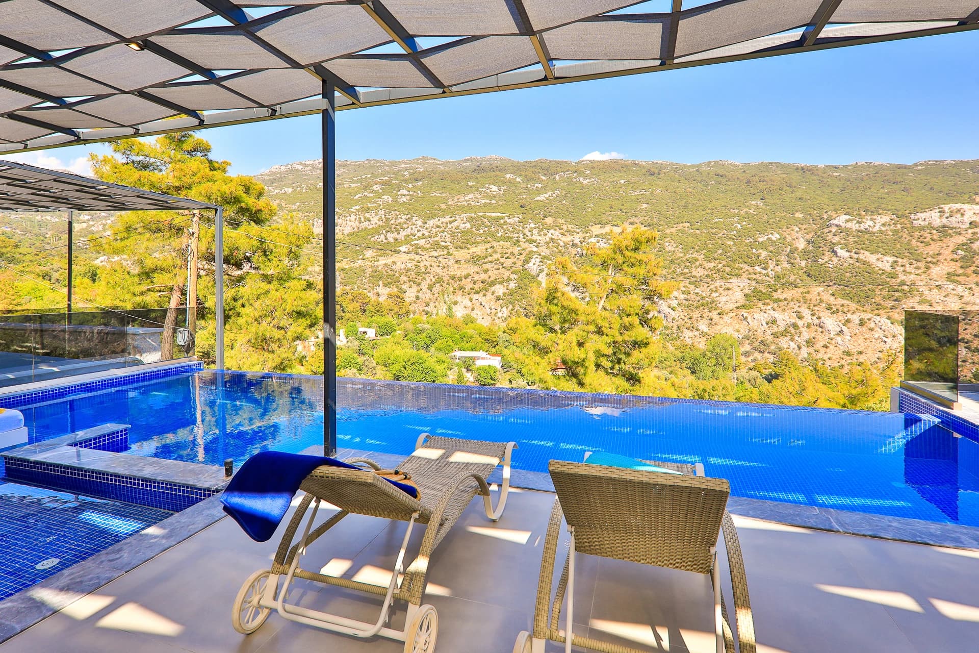 Stunning private pool overlooking rolling hills and valley landscape with loungers and pergola shade.