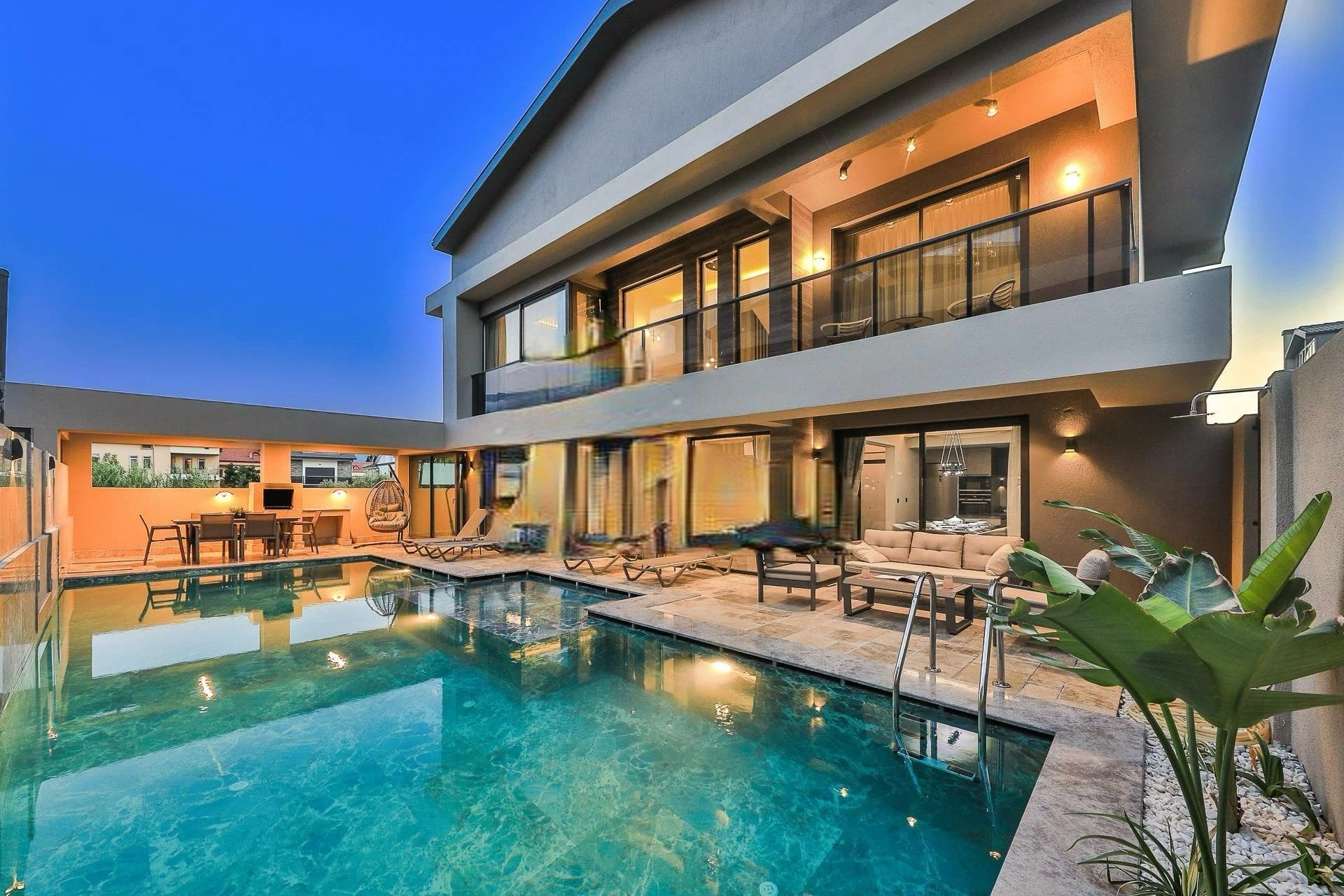 Stunning twilight view of the villa with heated private pool and lounging areas.