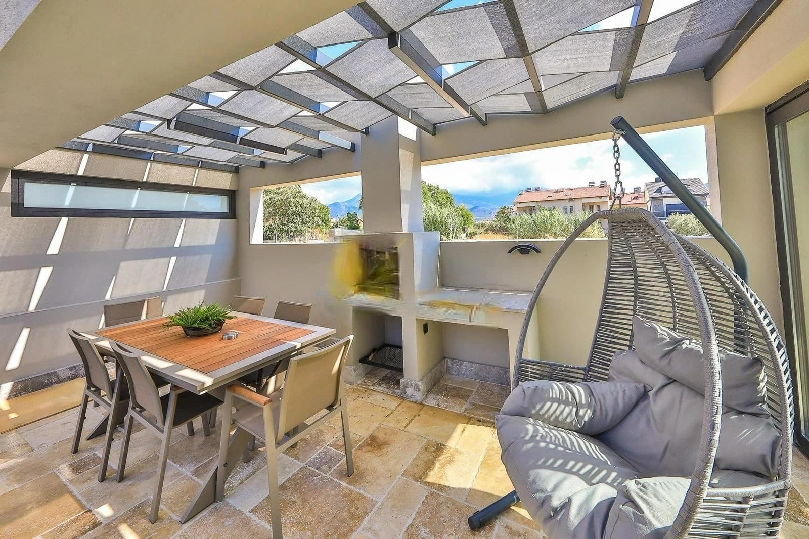 Covered terrace with outdoor dining and sea view with hanging chair.