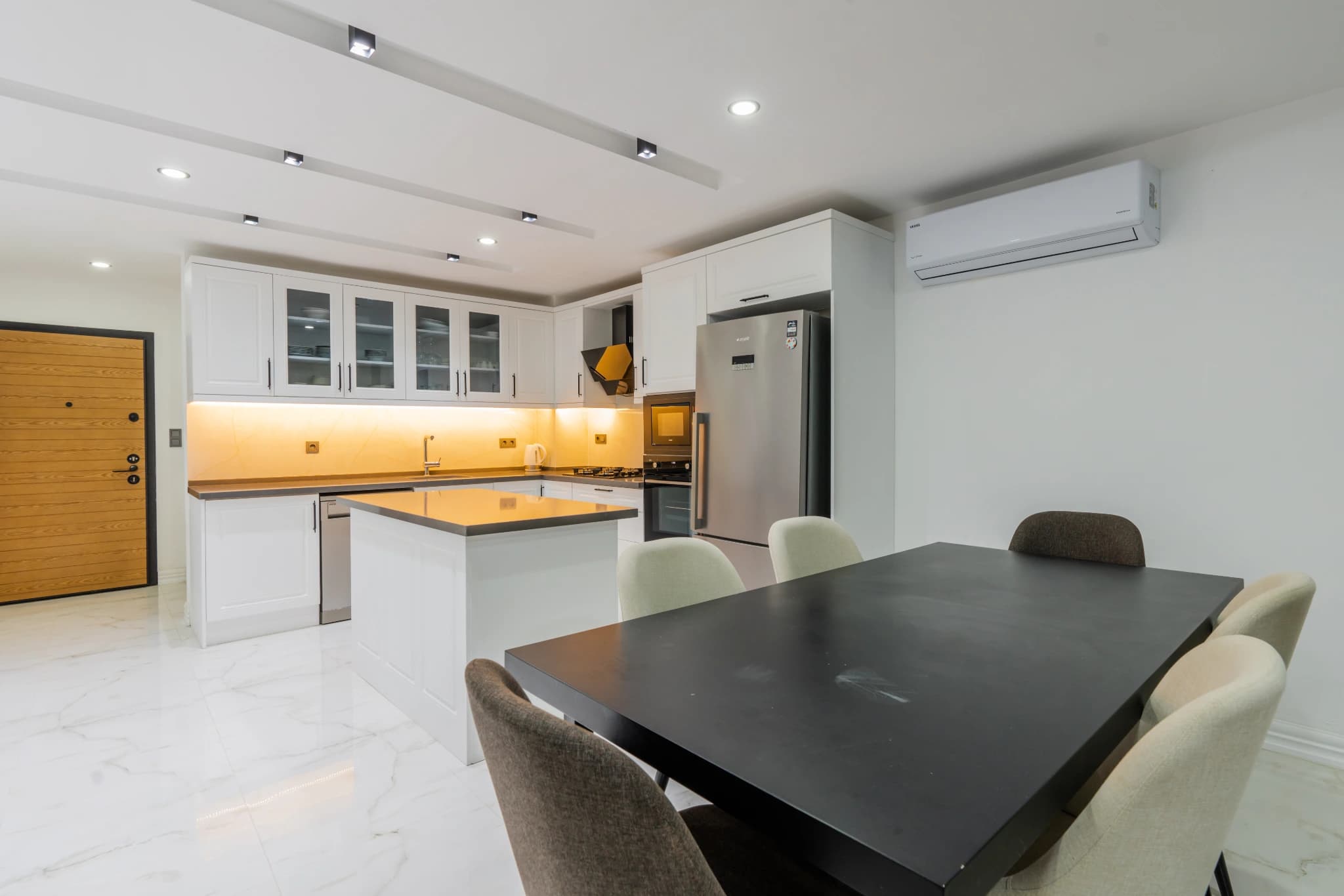 Dining room connected to kitchen with island counter and modern fixtures.
