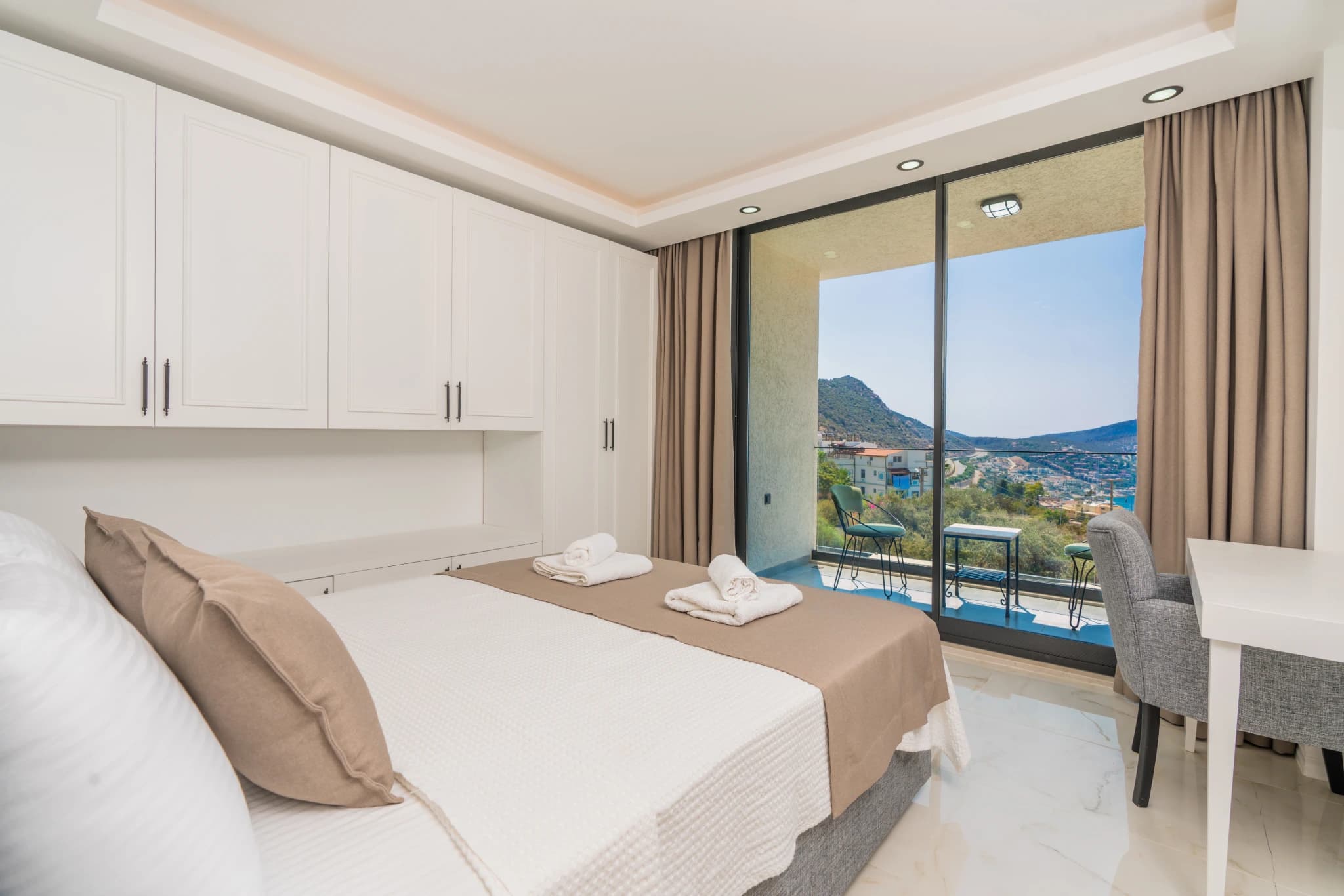 Spacious bedroom with queen bed, floor-to-ceiling windows, and stunning sea view from the balcony.