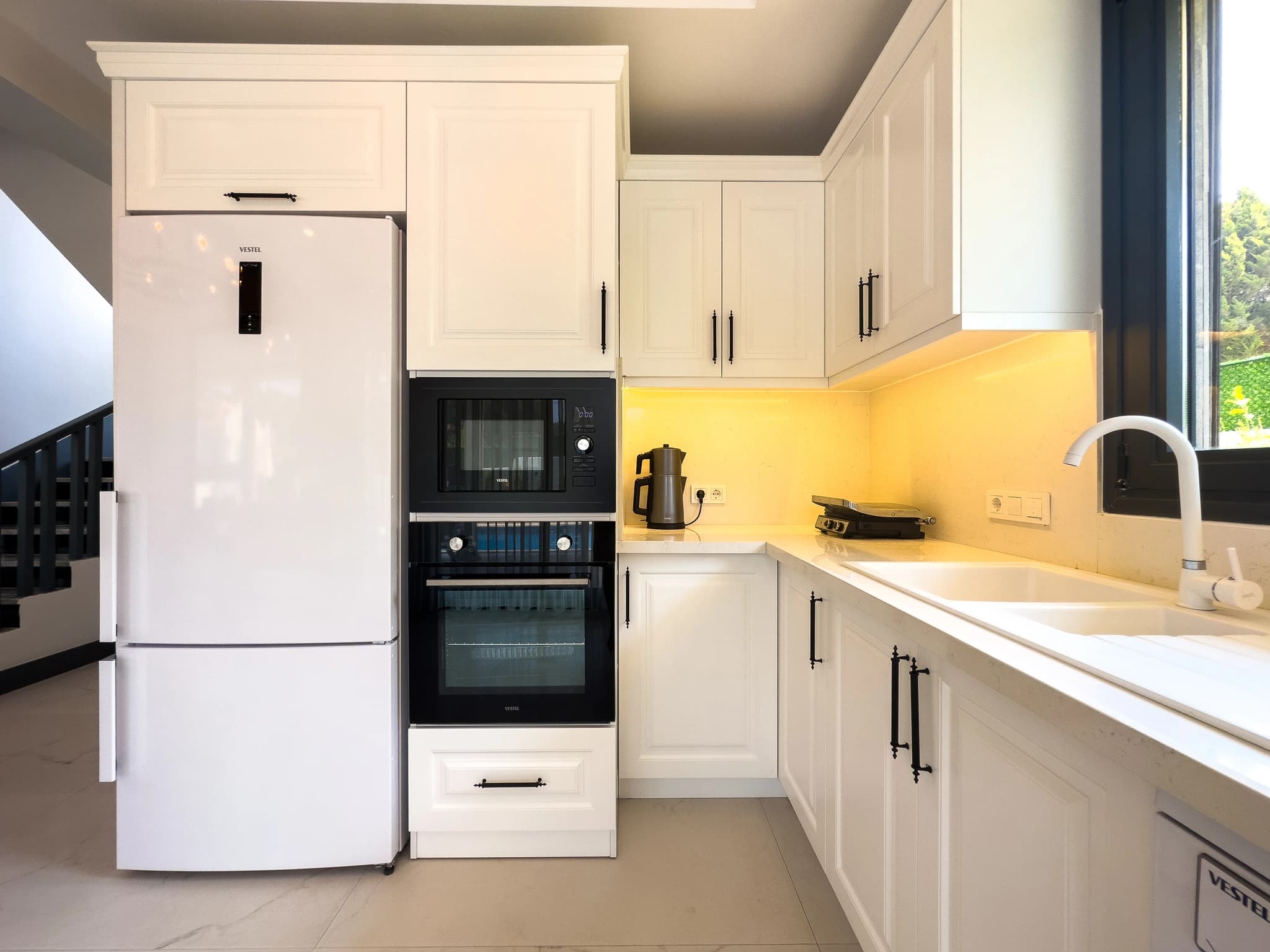 Contemporary kitchen corner showcasing white cabinetry, integrated appliances, and bright yellow accent lighting.