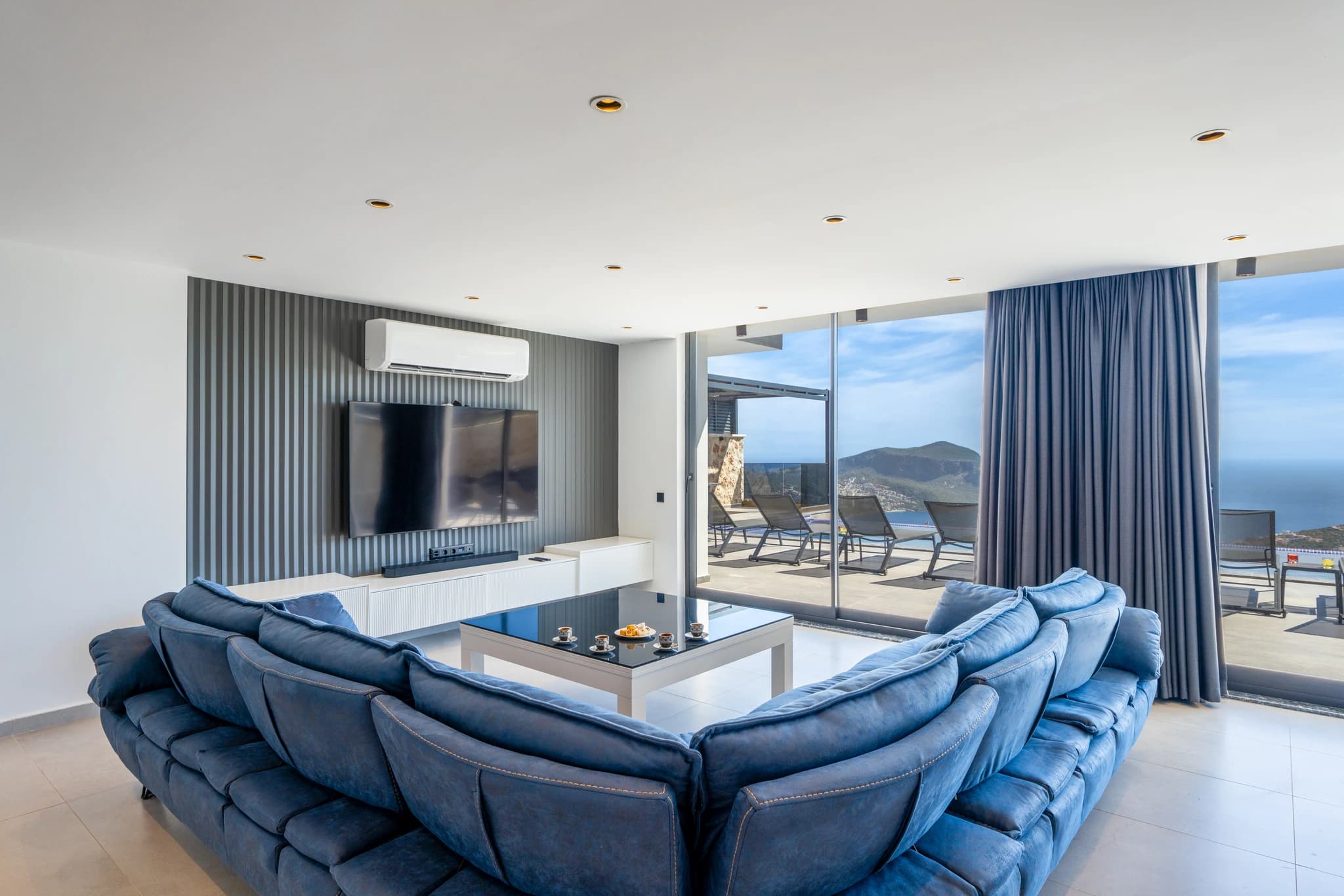 Luxurious lounge with exceptional seascape views, modern furnishings, and floor-to-ceiling windows opening to terrace.