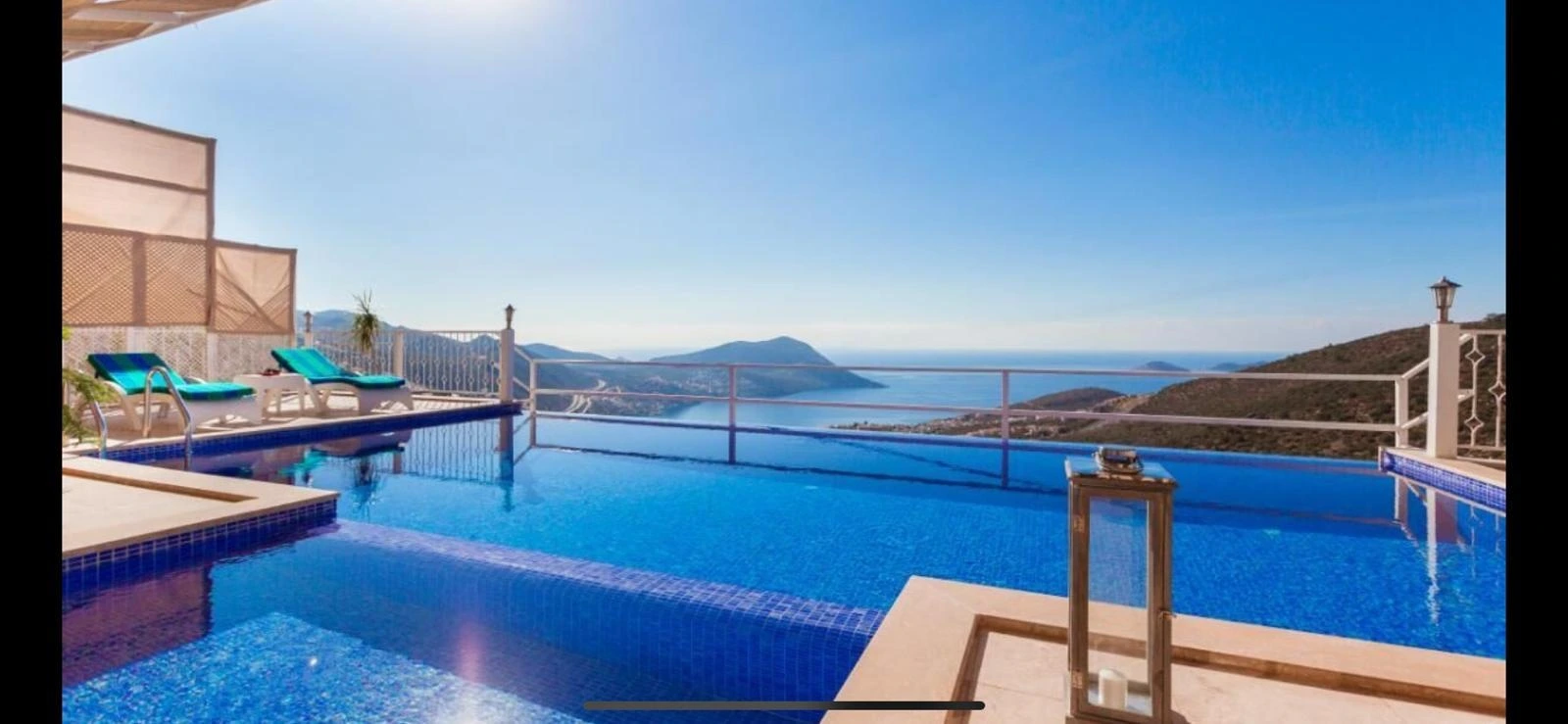 Stunning infinity pool overlooking the sparkling sea and coastal mountains.
