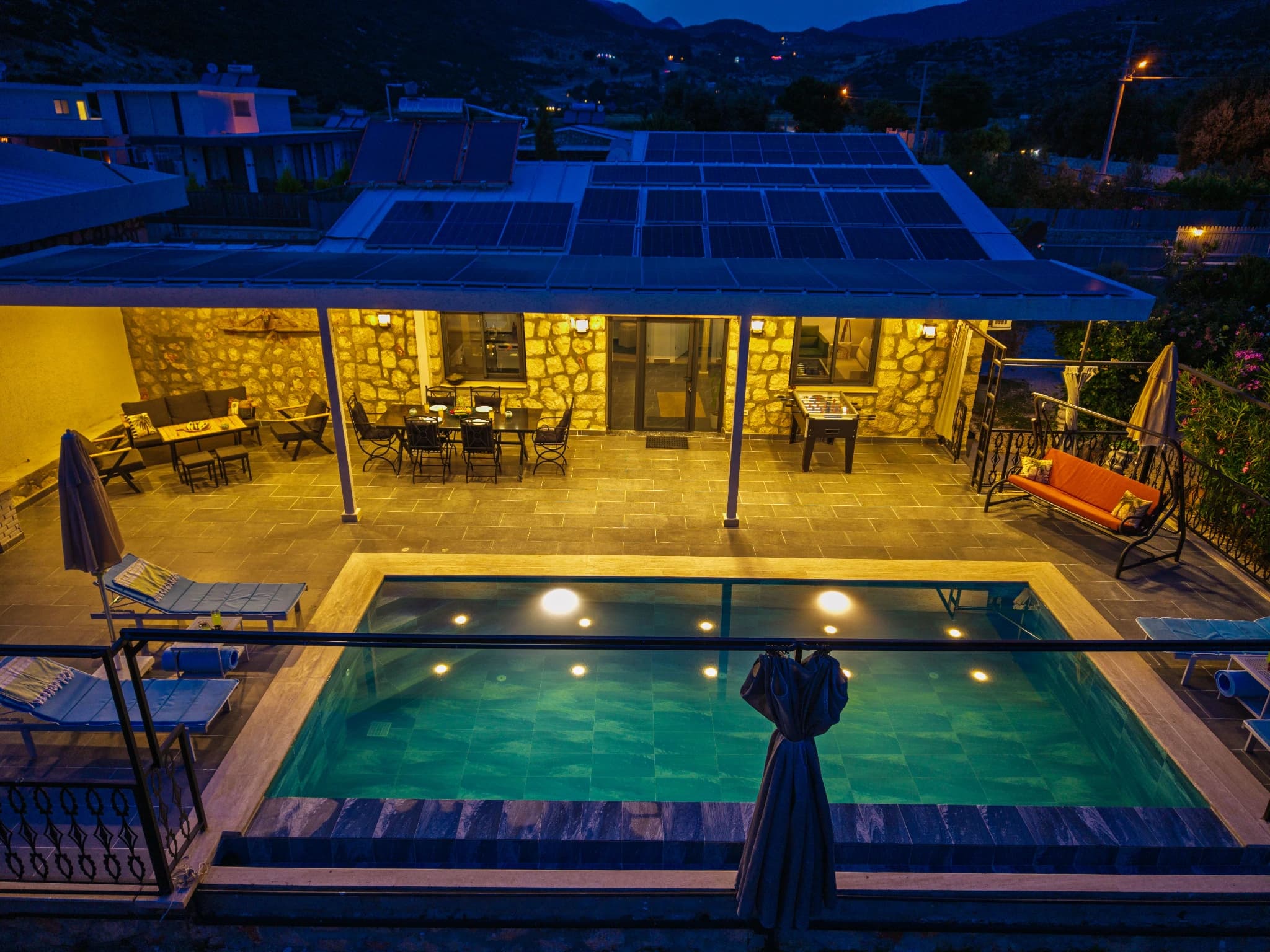 Spacious terrace with private pool, outdoor dining area, and mountain views at twilight.