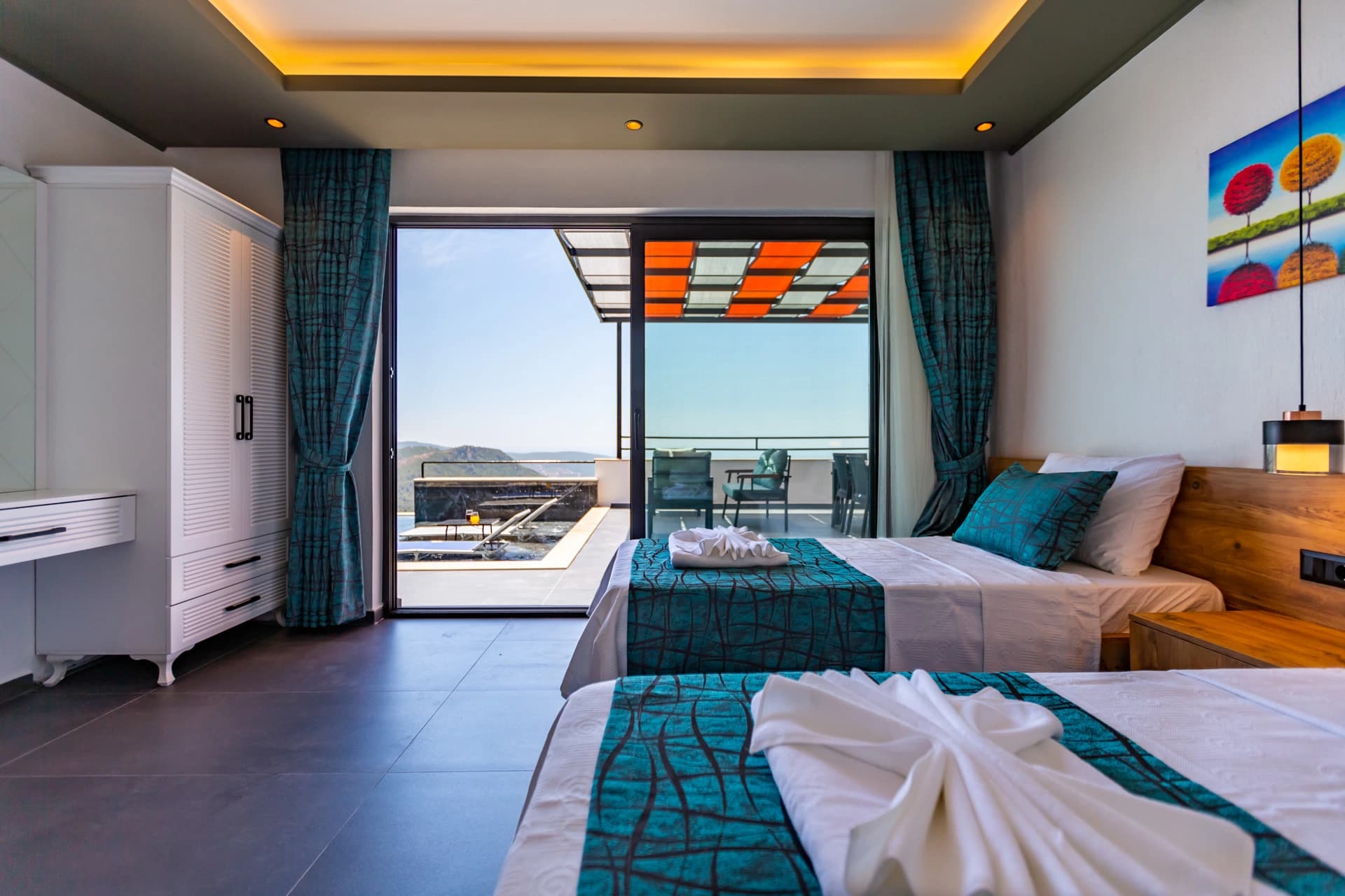 Guest bedroom featuring twin beds, expansive balcony, and sweeping coastal views.