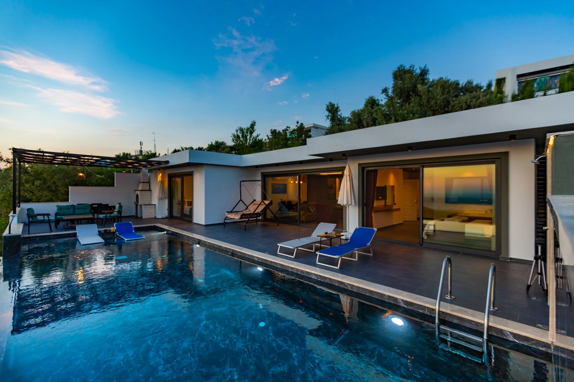 Modern terrace with pool and lounging area at dusk.