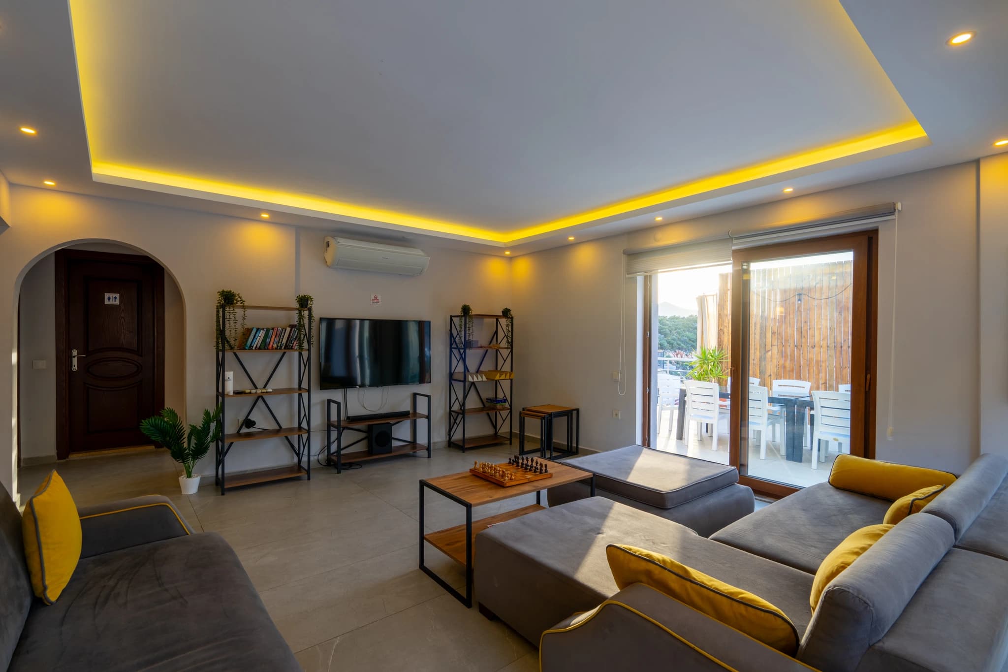 Spacious modern living room with comfortable seating, entertainment system, and scenic terrace access.