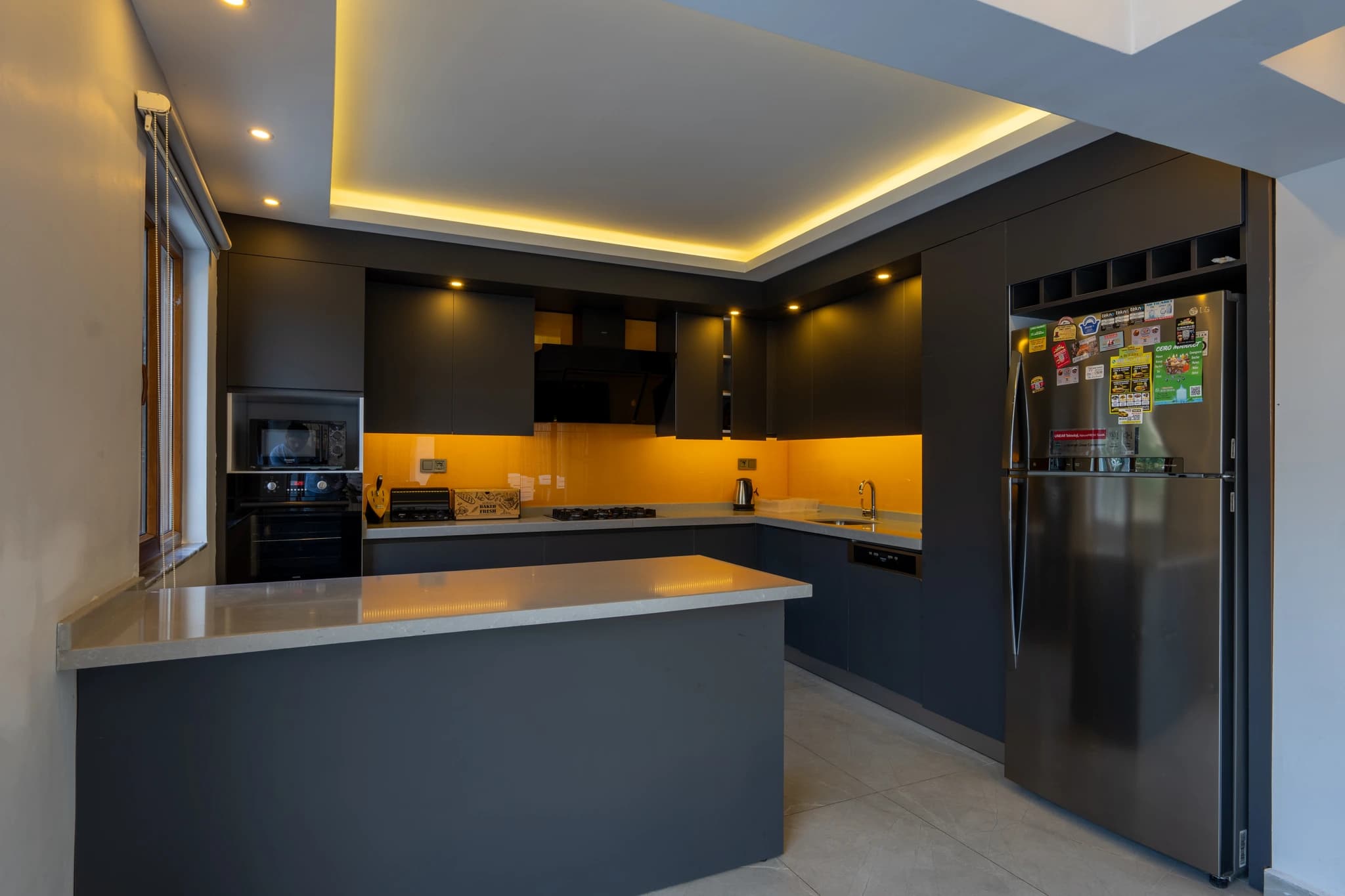 Modern kitchen with bold black and orange design, stainless steel appliances, and spacious island.