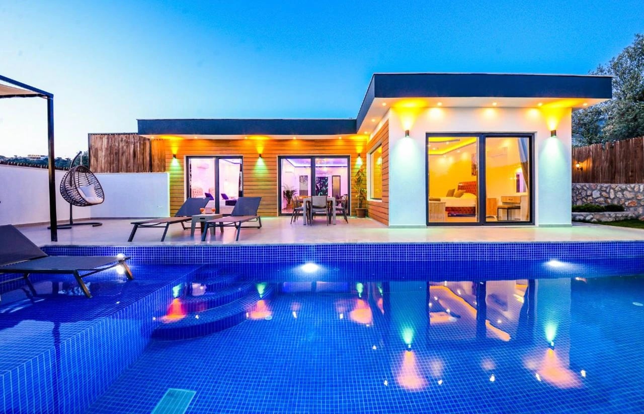 Stunning illuminated pool at dusk with modern architecture and comfortable lounging zones.