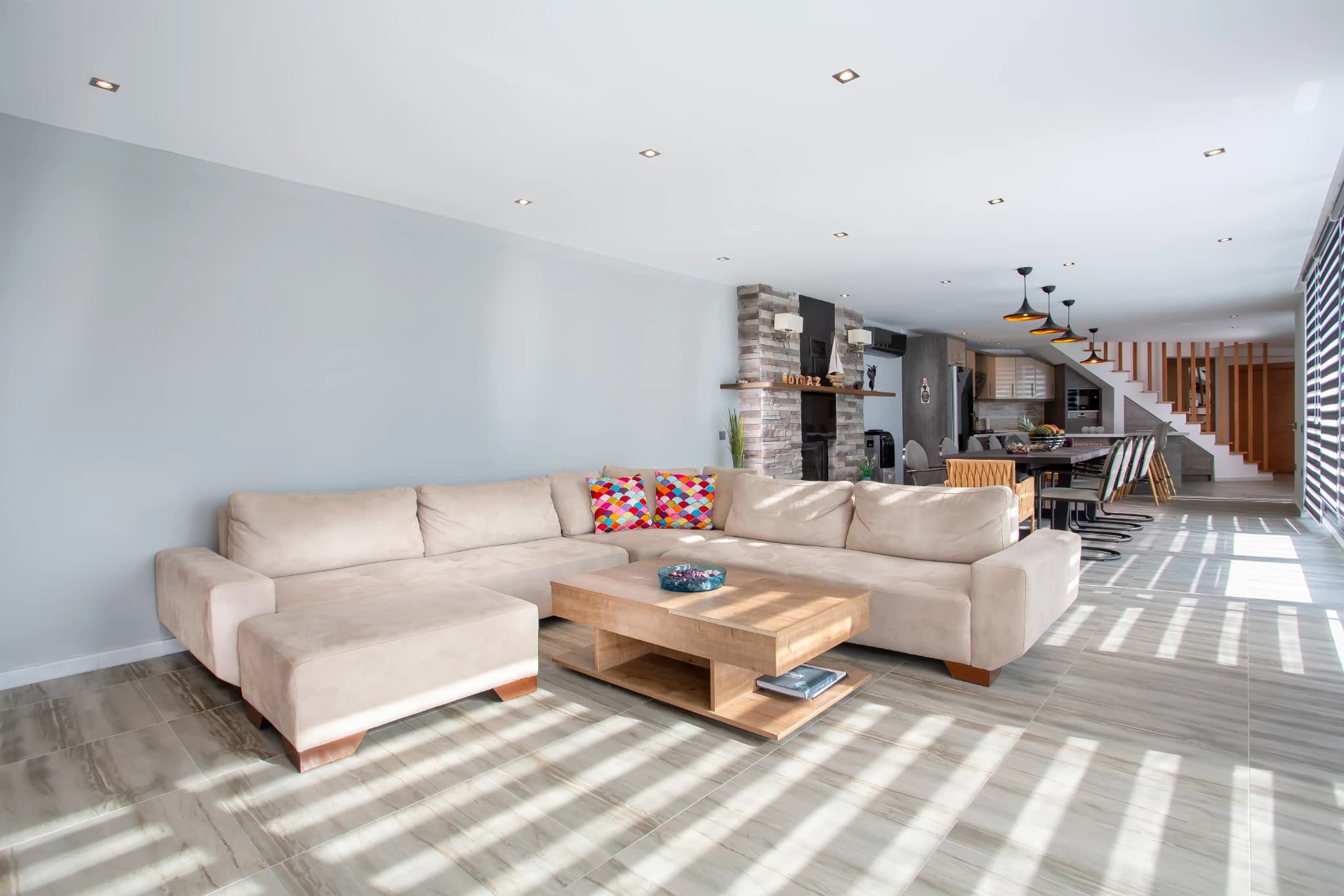 Spacious living room with beige sectional sofa and fireplace feature.